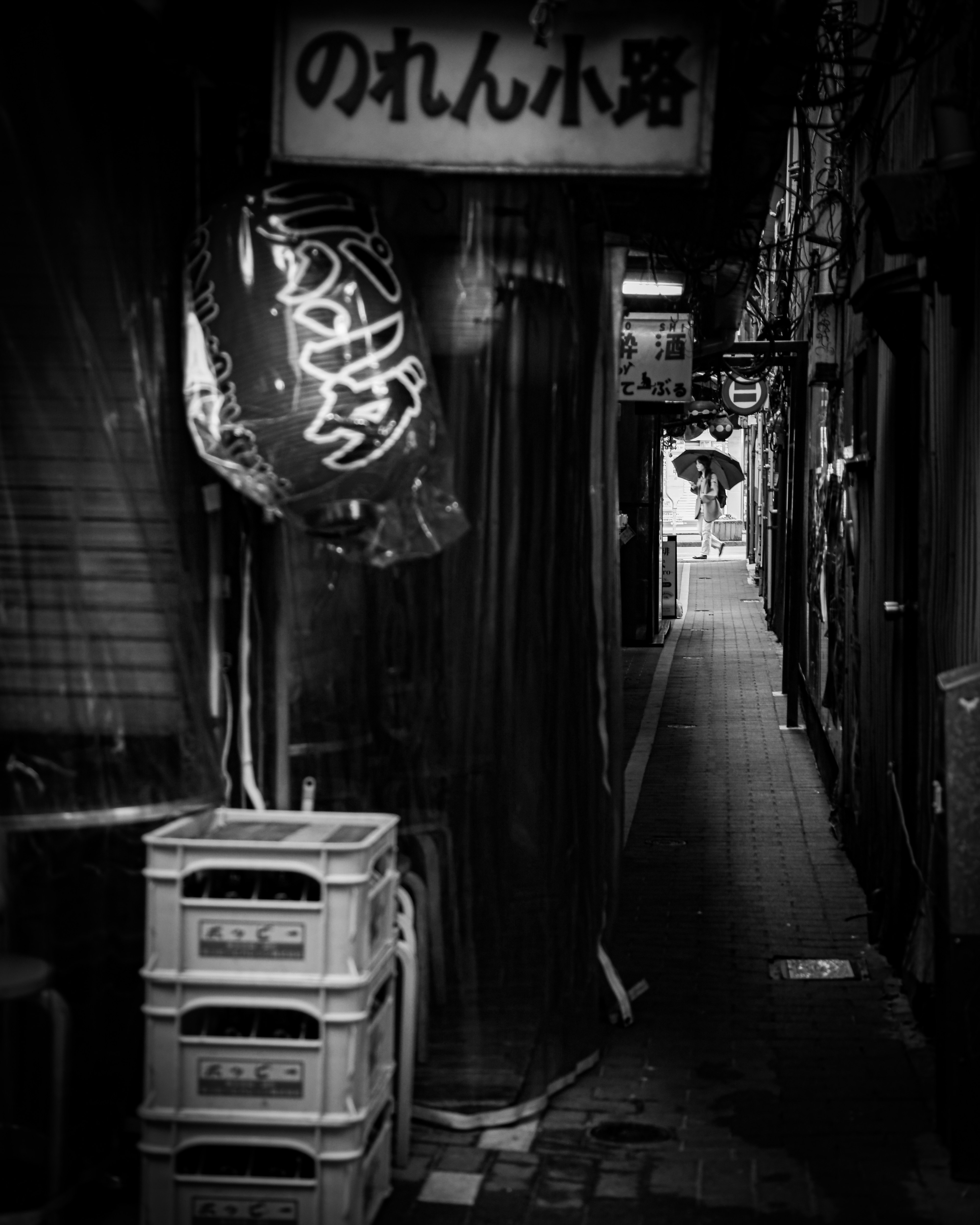 Une ruelle étroite avec des lanternes lumineuses et une enseigne dans un cadre sombre