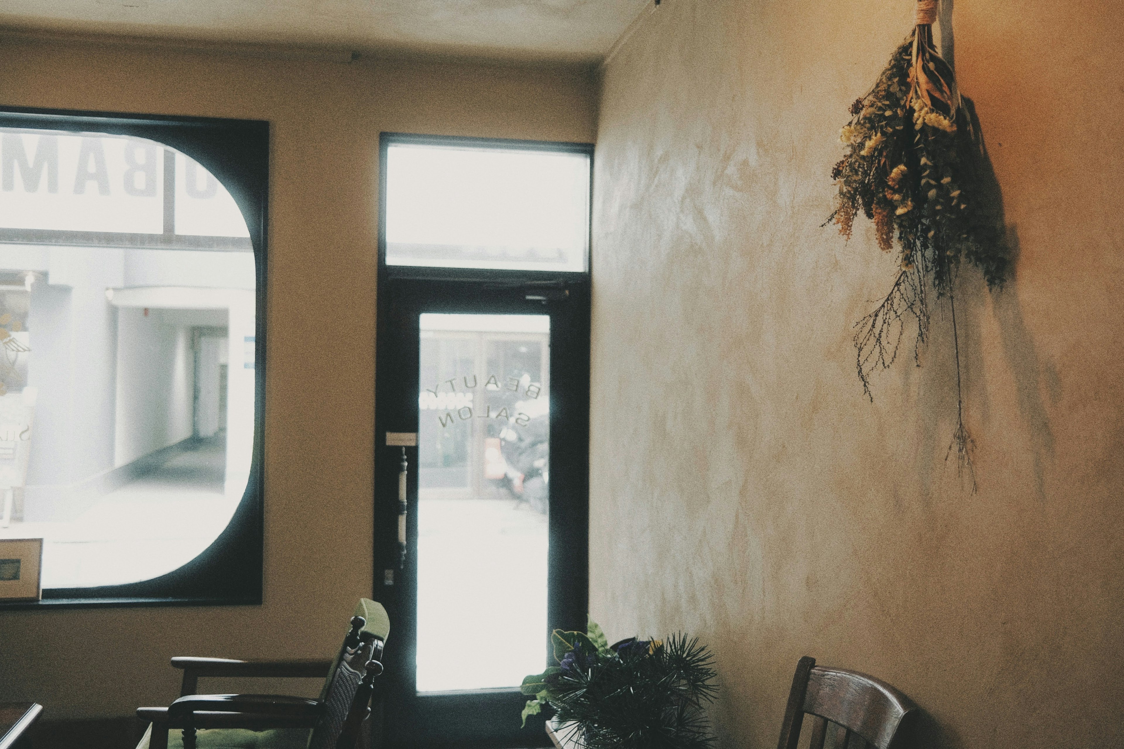 Vista interior de una cafetería con una pared decorada con plantas y una puerta que da al exterior