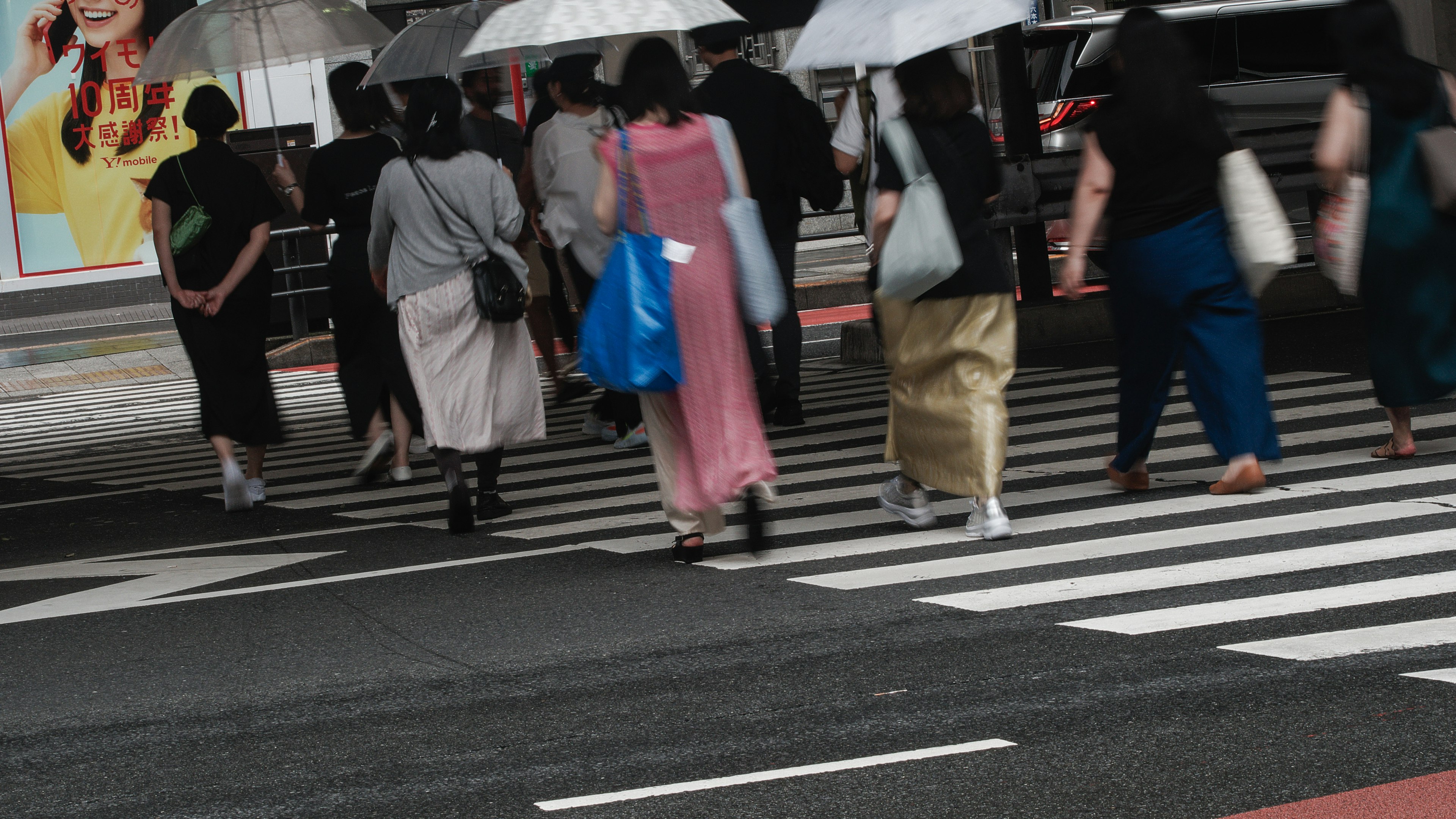 傘を持った人々が横断歩道を渡る様子