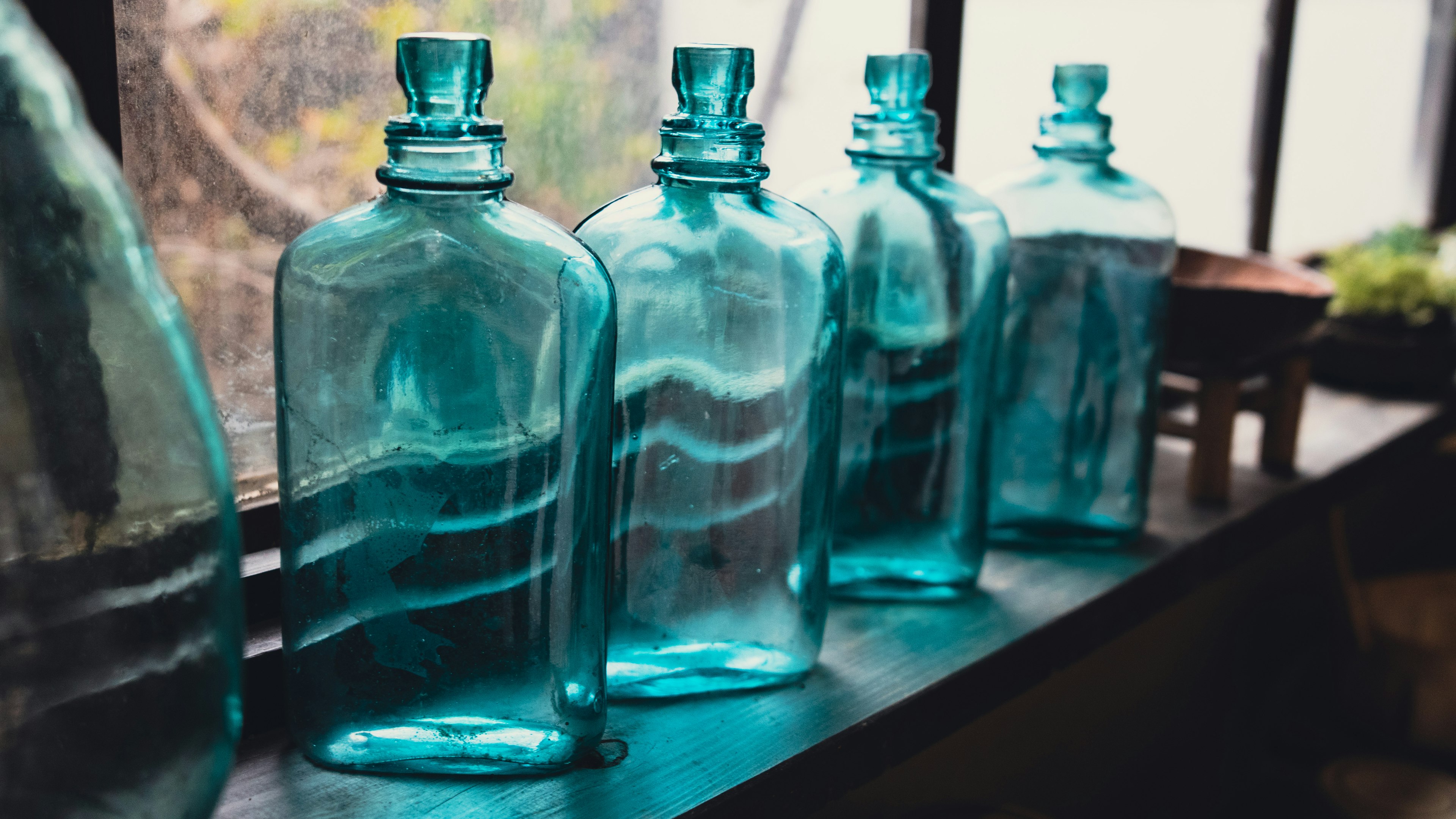 Rang de bouteilles en verre bleu sur un rebord de fenêtre avec lumière naturelle