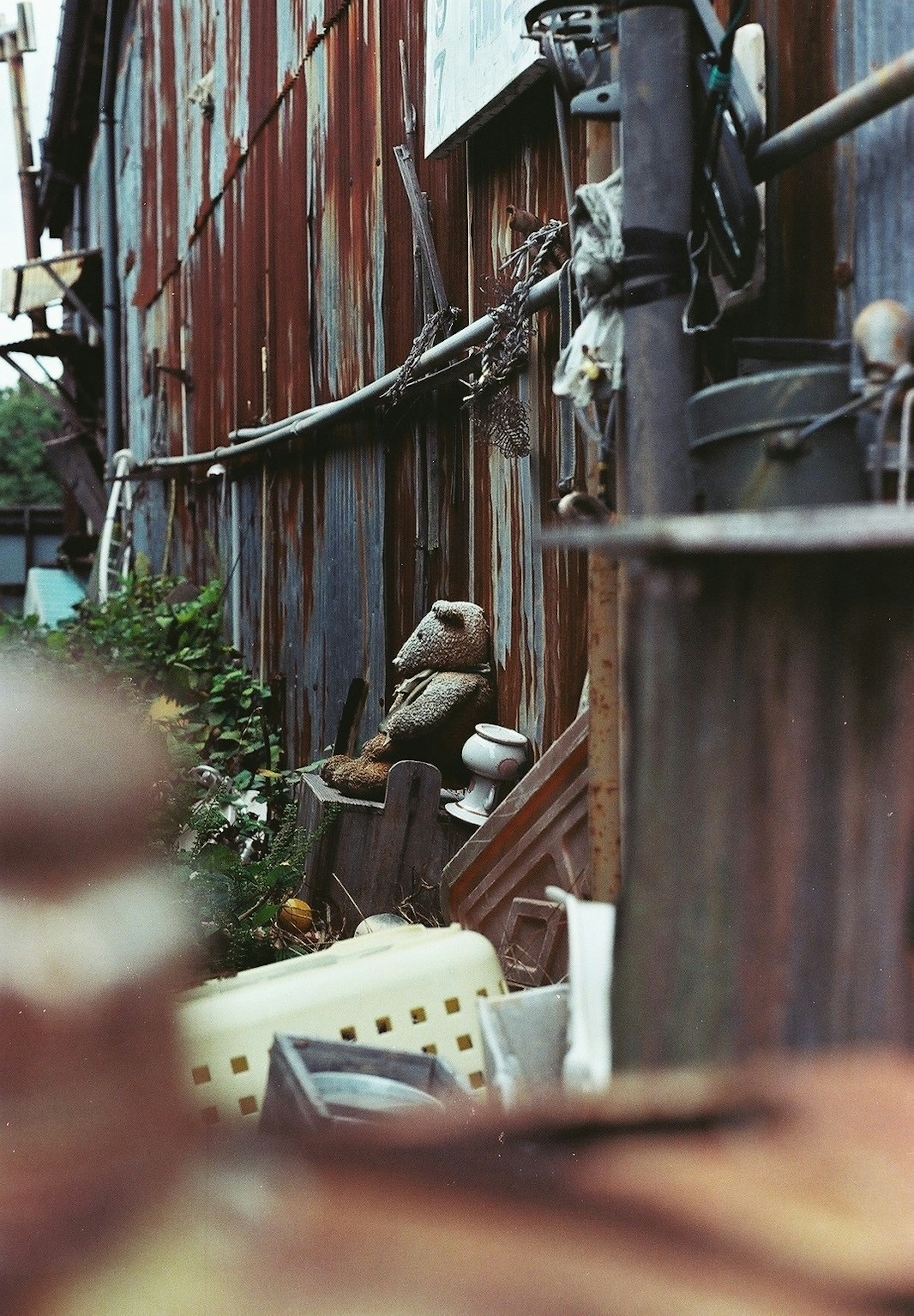 Una figura parecida a una muñeca entre objetos desechados en un fondo de metal oxidado