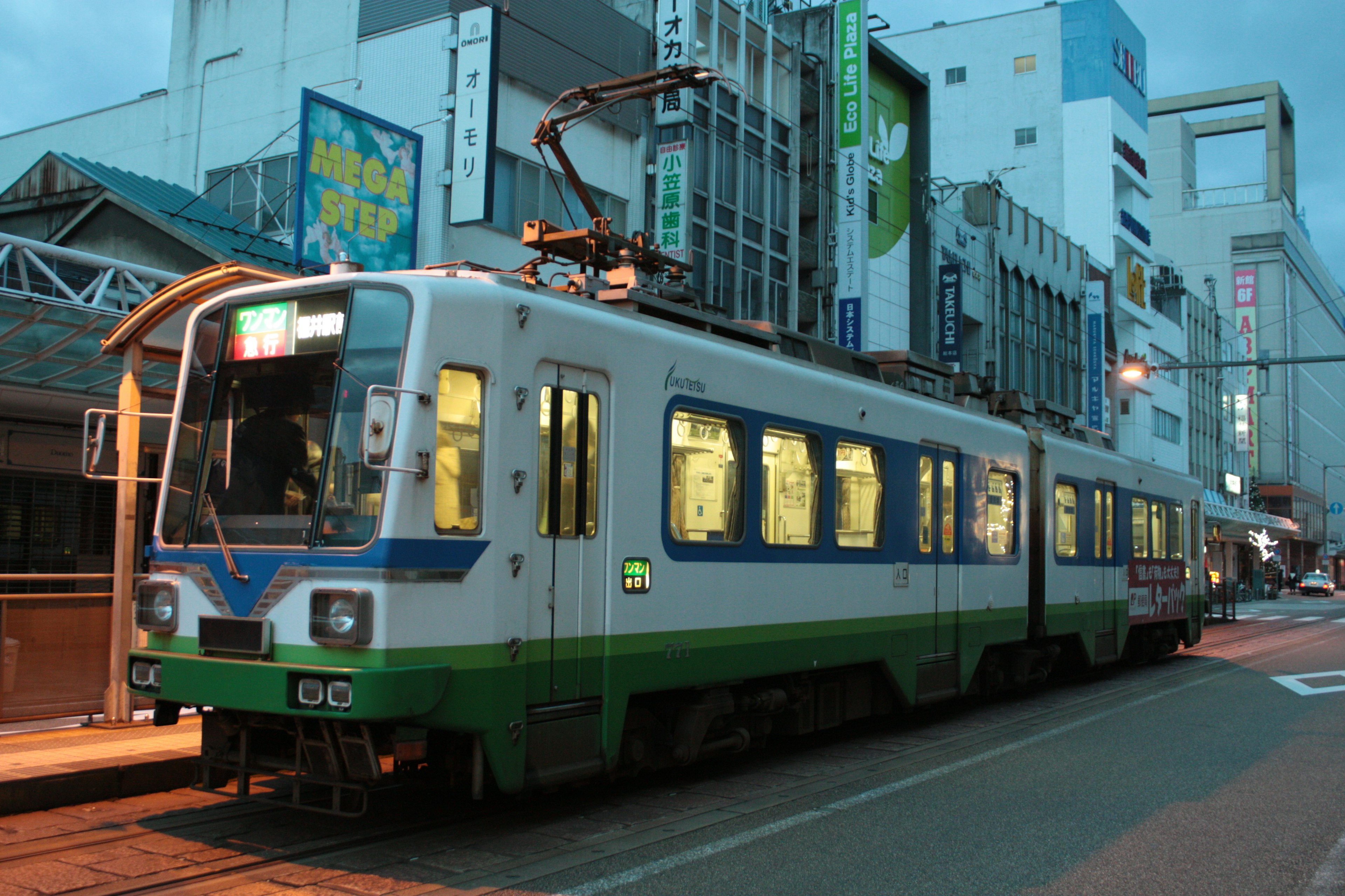 Un train vert et blanc garé dans la ville la nuit