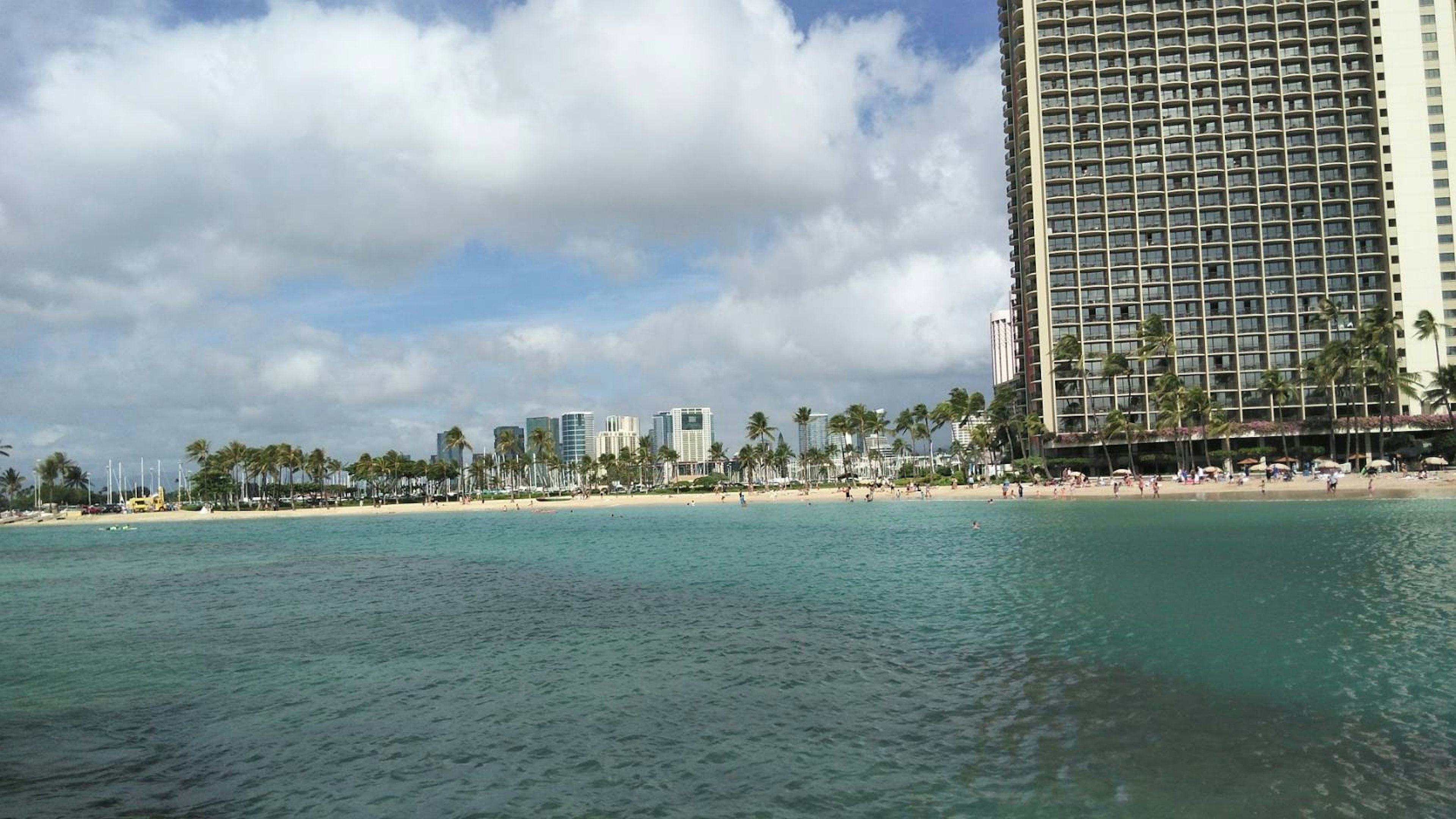 Panoramablick auf den Waikiki-Strand mit einem Hochhaus und türkisfarbenem Wasser