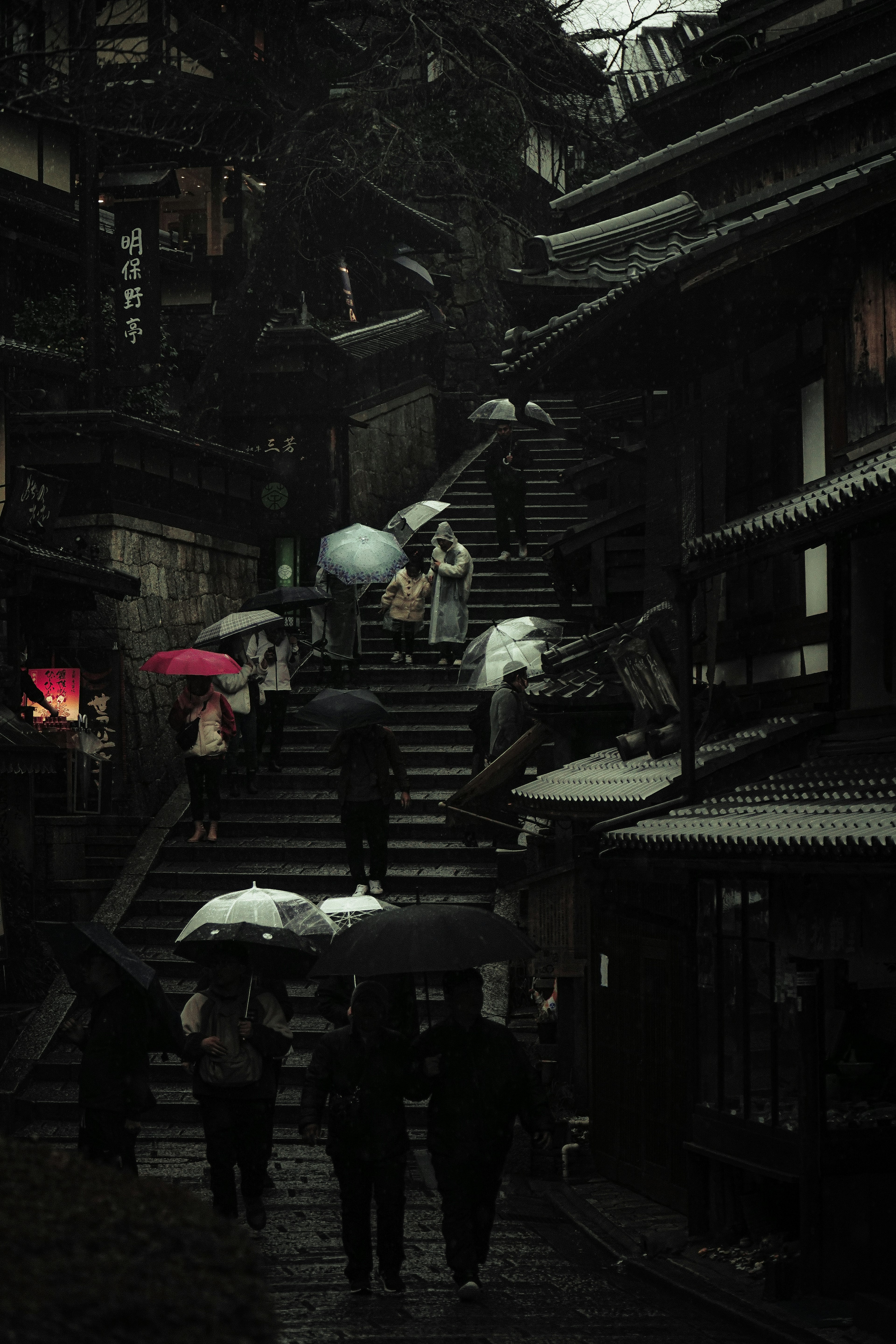 People walking up stairs in the rain with umbrellas and ancient buildings