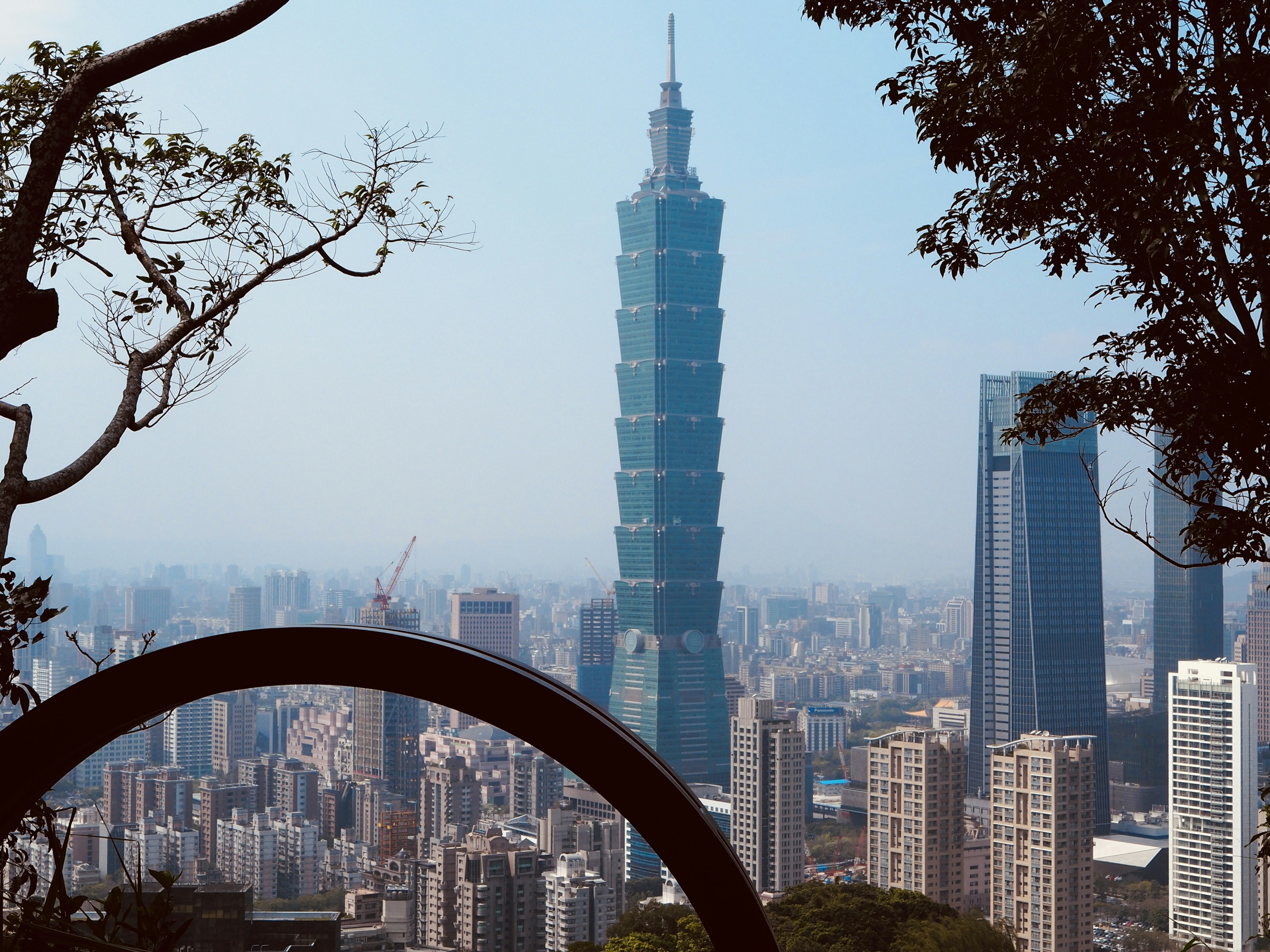 Pemandangan kota dengan menara Taipei 101 dikelilingi oleh pepohonan