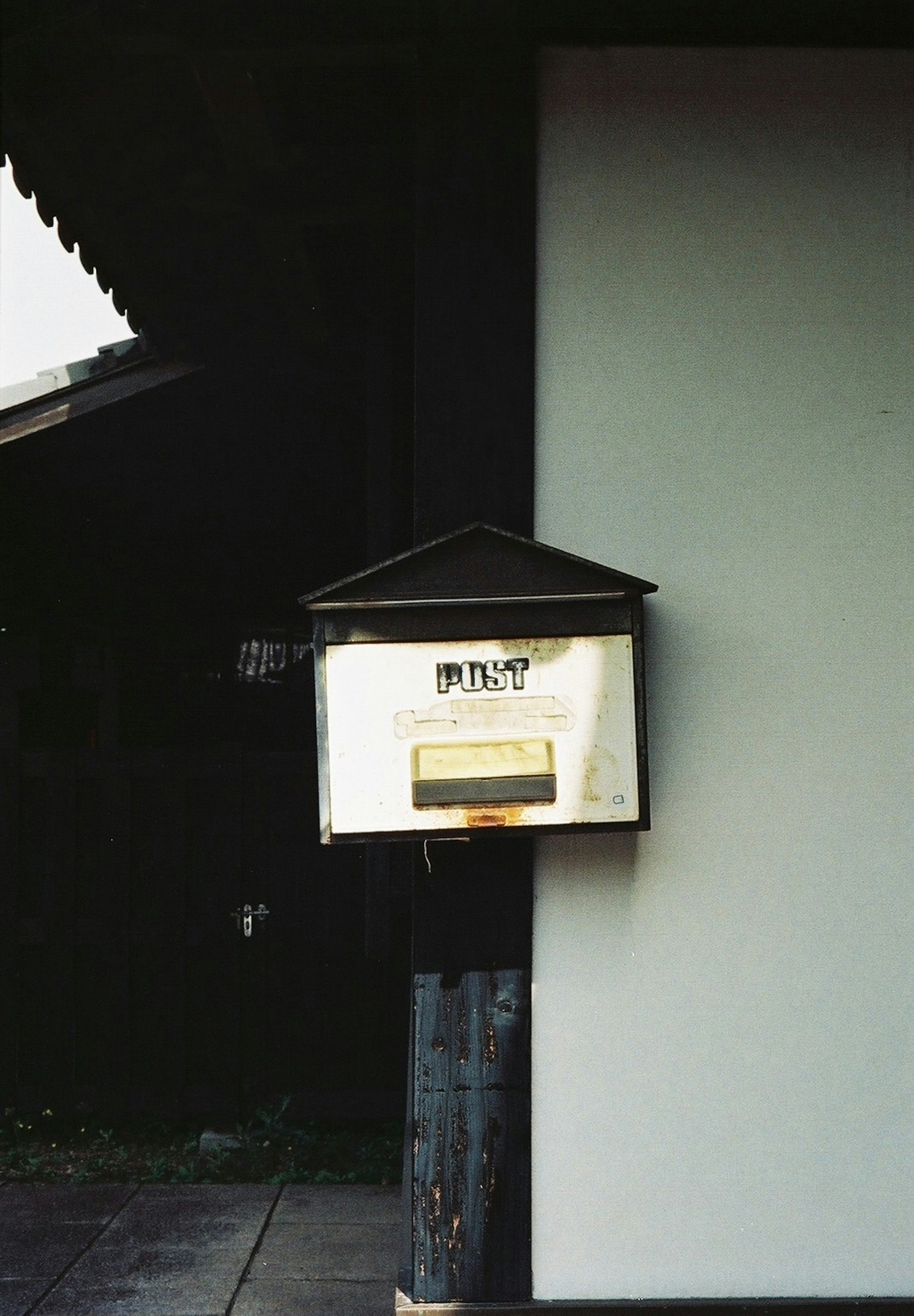 An old mailbox mounted on a white wall