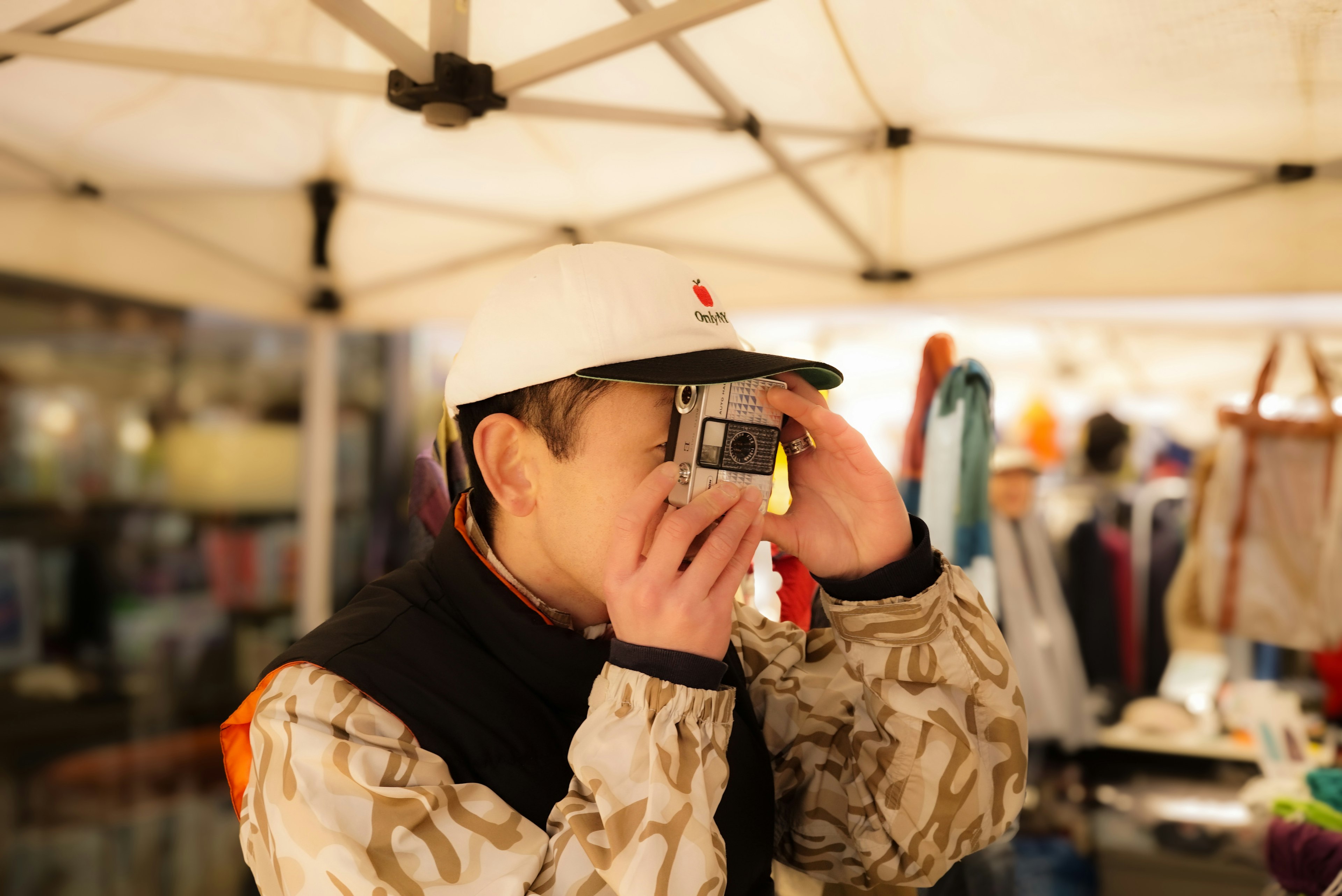 A person taking a photo with a camera under a tent