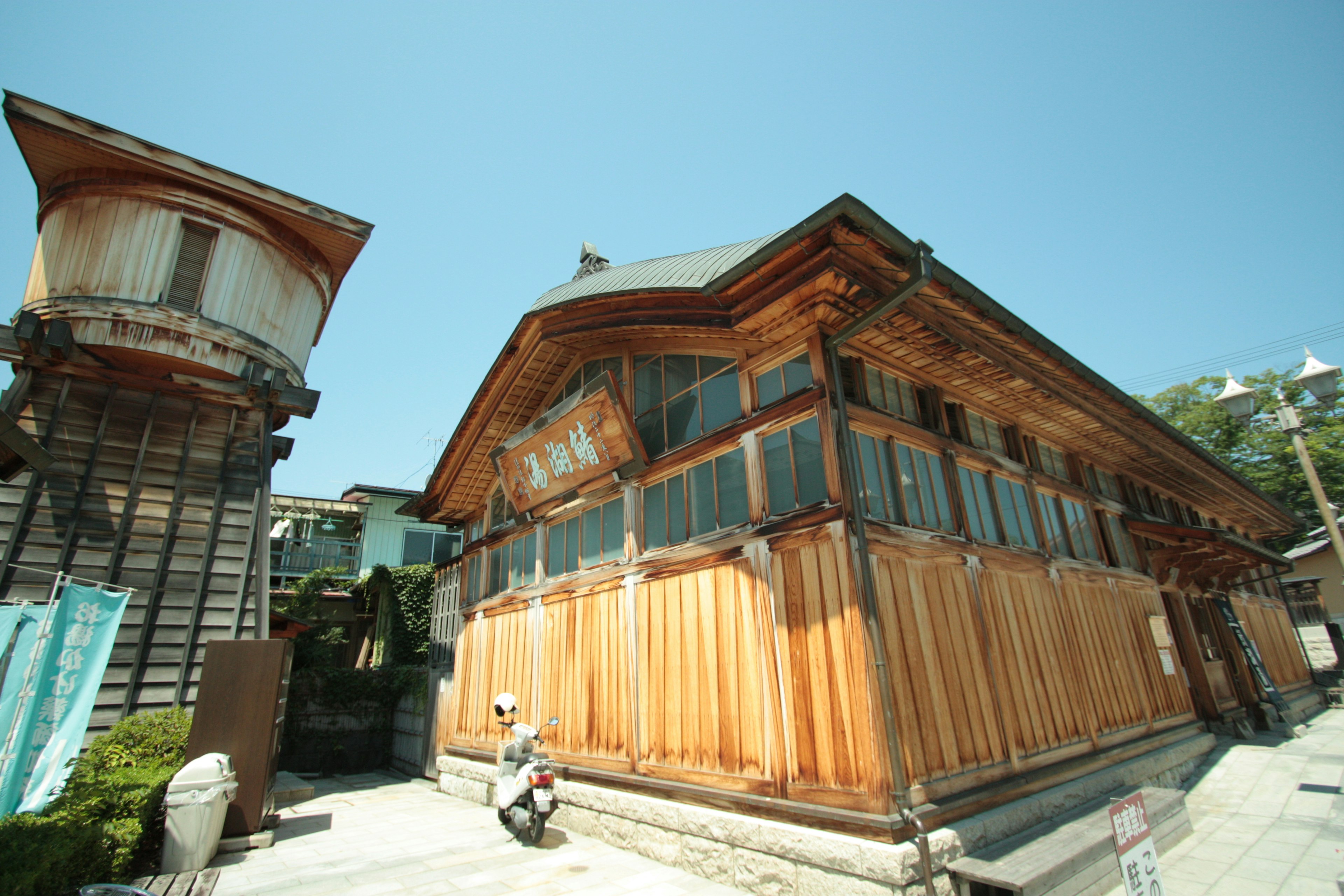 木造の伝統的な建物と水塔が青空の下にある風景