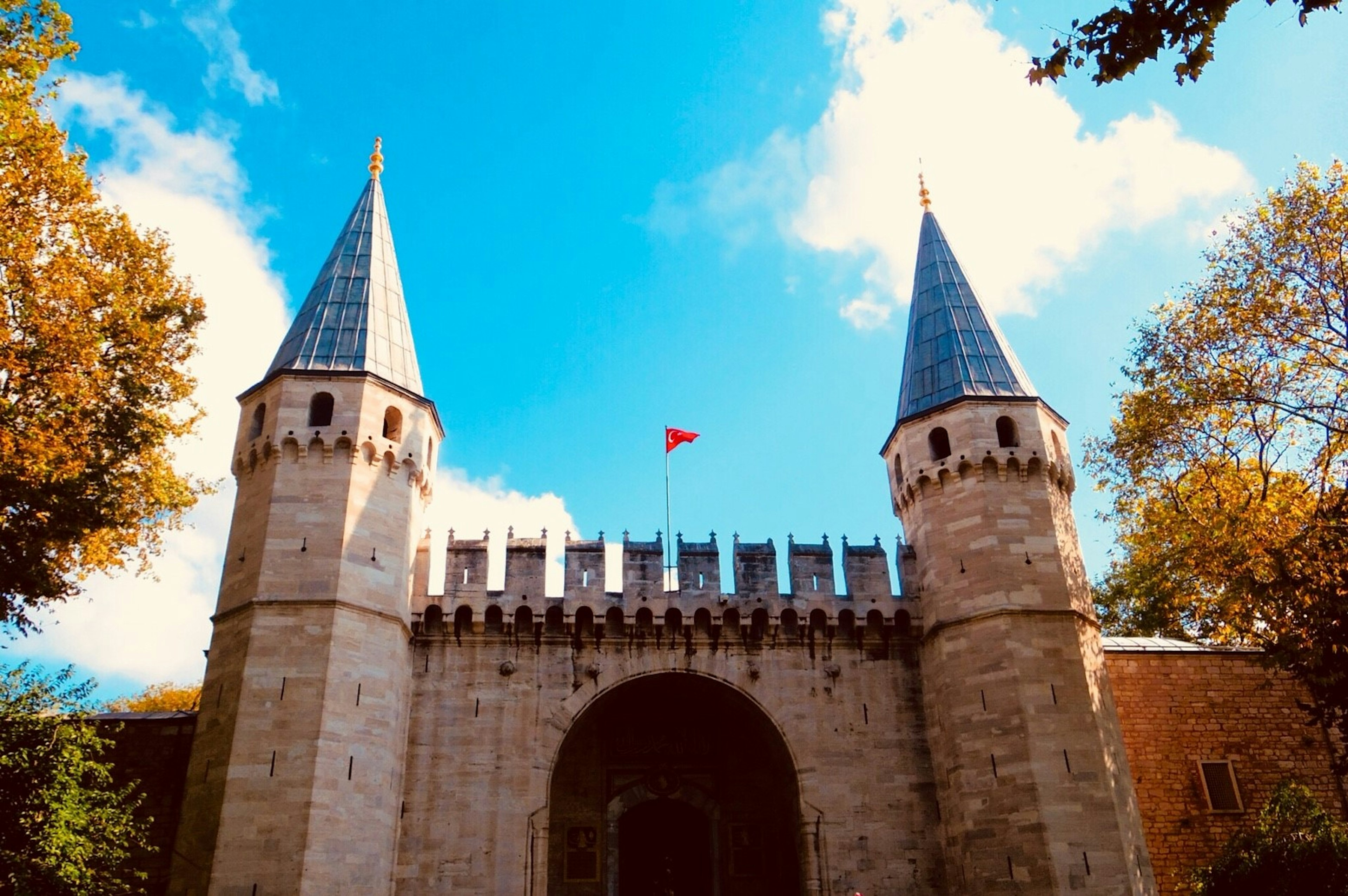 Historic castle entrance with two pointed towers under a blue sky