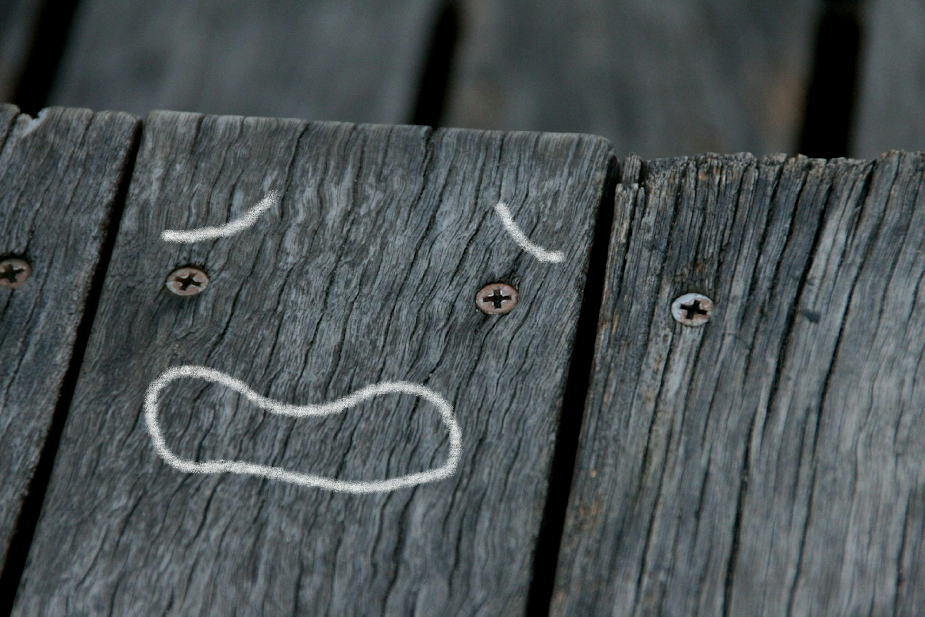 Una cara triste dibujada en una tabla de madera