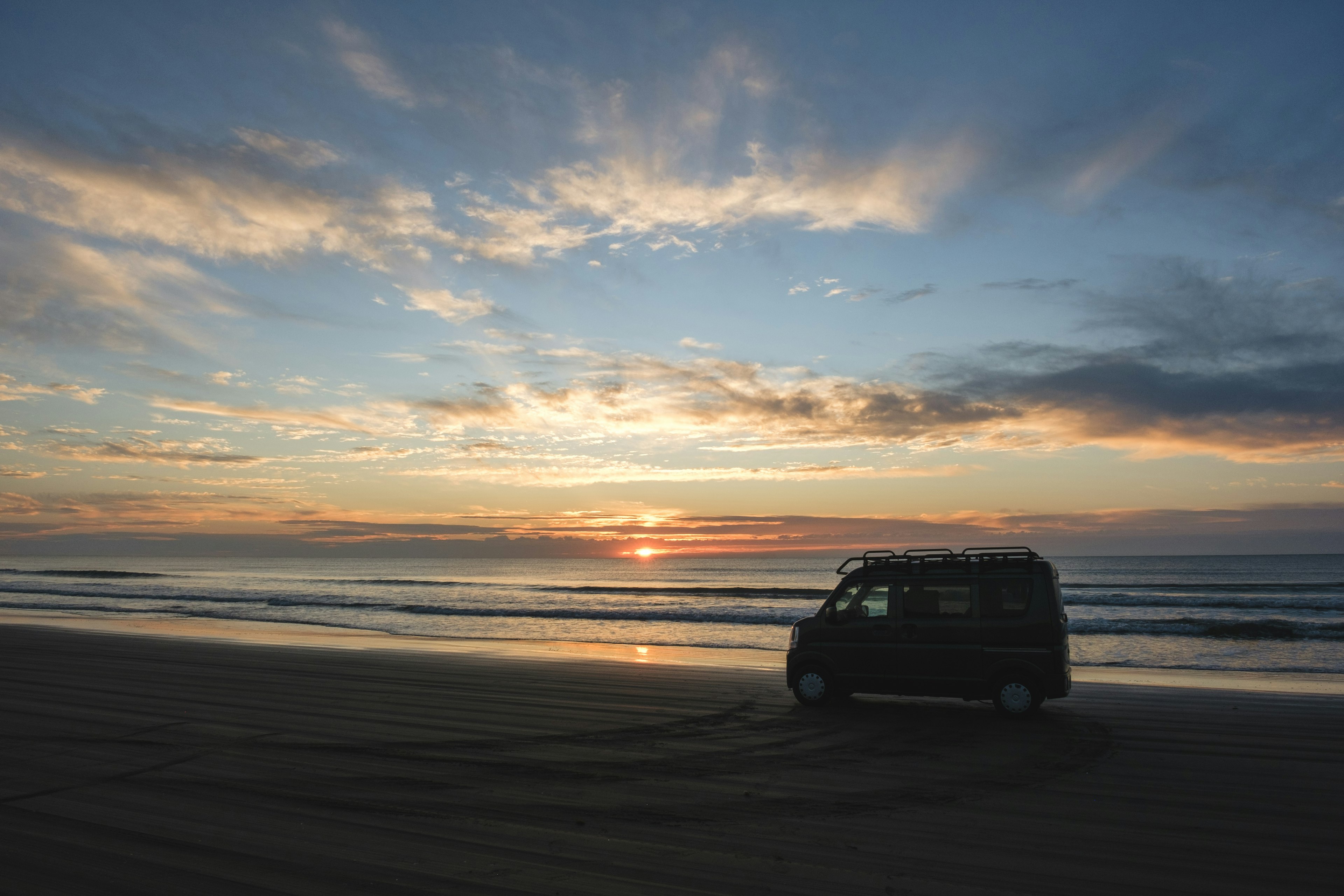 Van vert sur la plage au coucher de soleil avec ciel coloré et océan