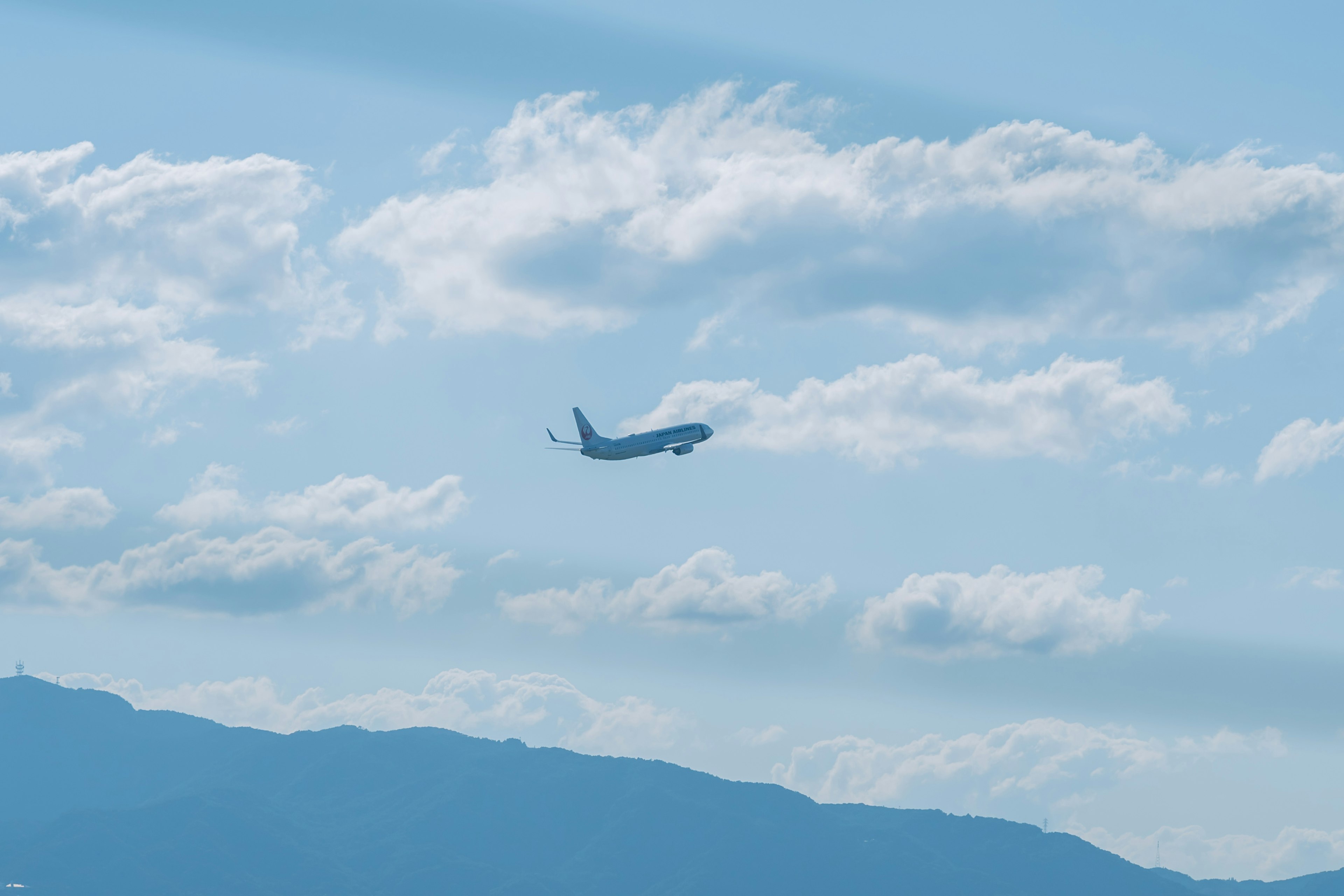 Un avión volando contra un cielo azul con nubes