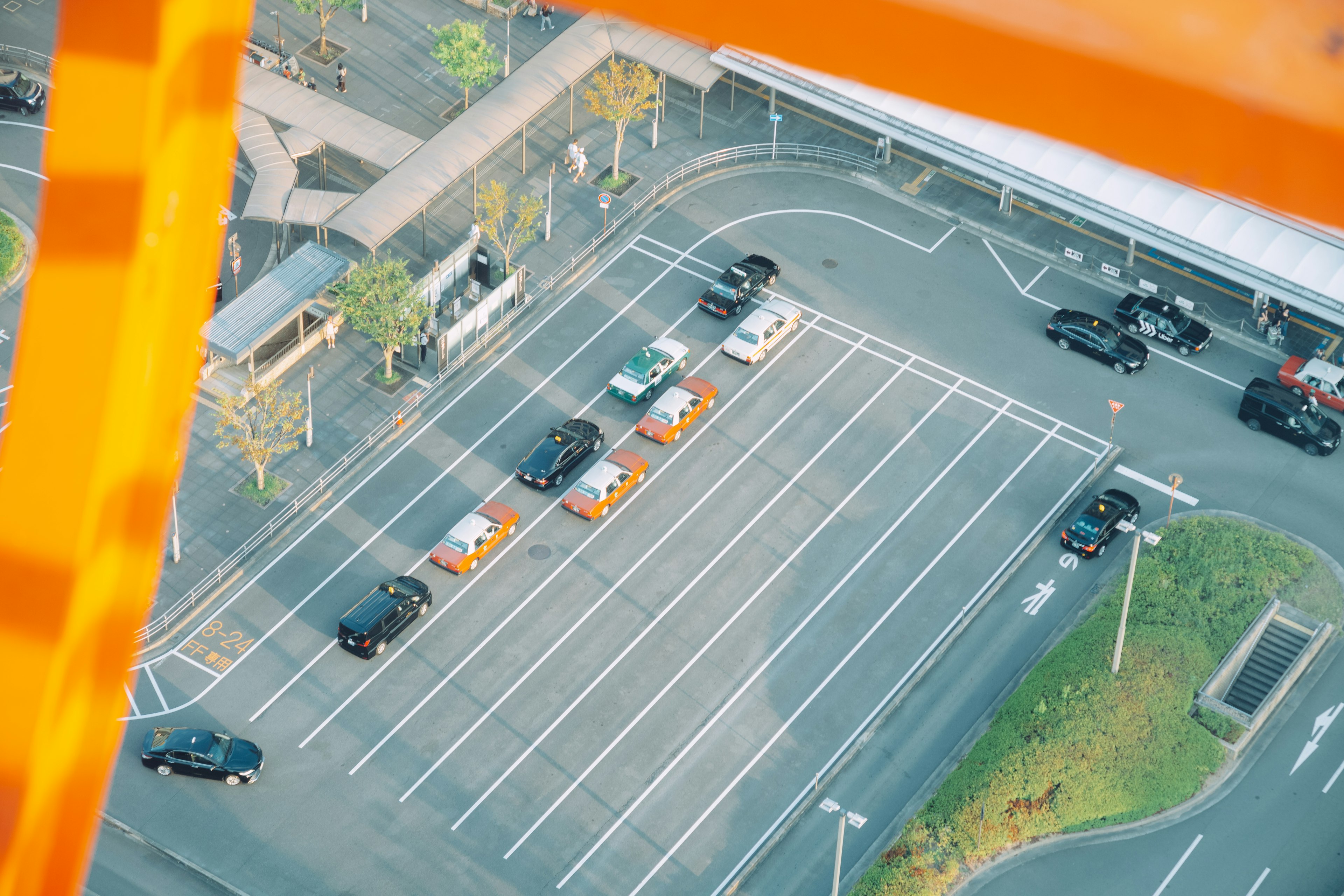 Vista aérea de un estacionamiento con autos y carreteras circundantes enmarcadas en naranja