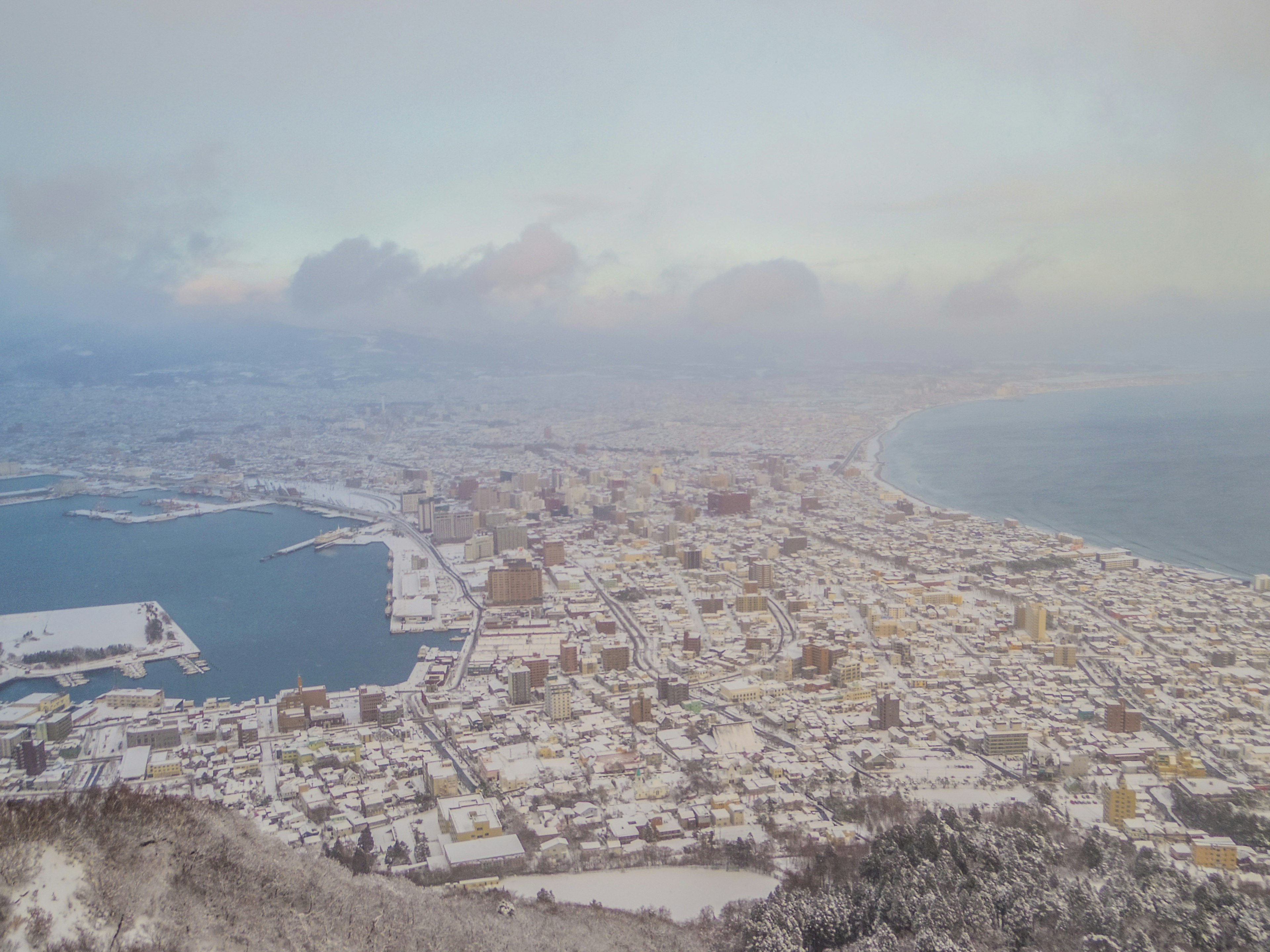 Panoramablick auf eine schneebedeckte Stadt mit Küste und Bergen