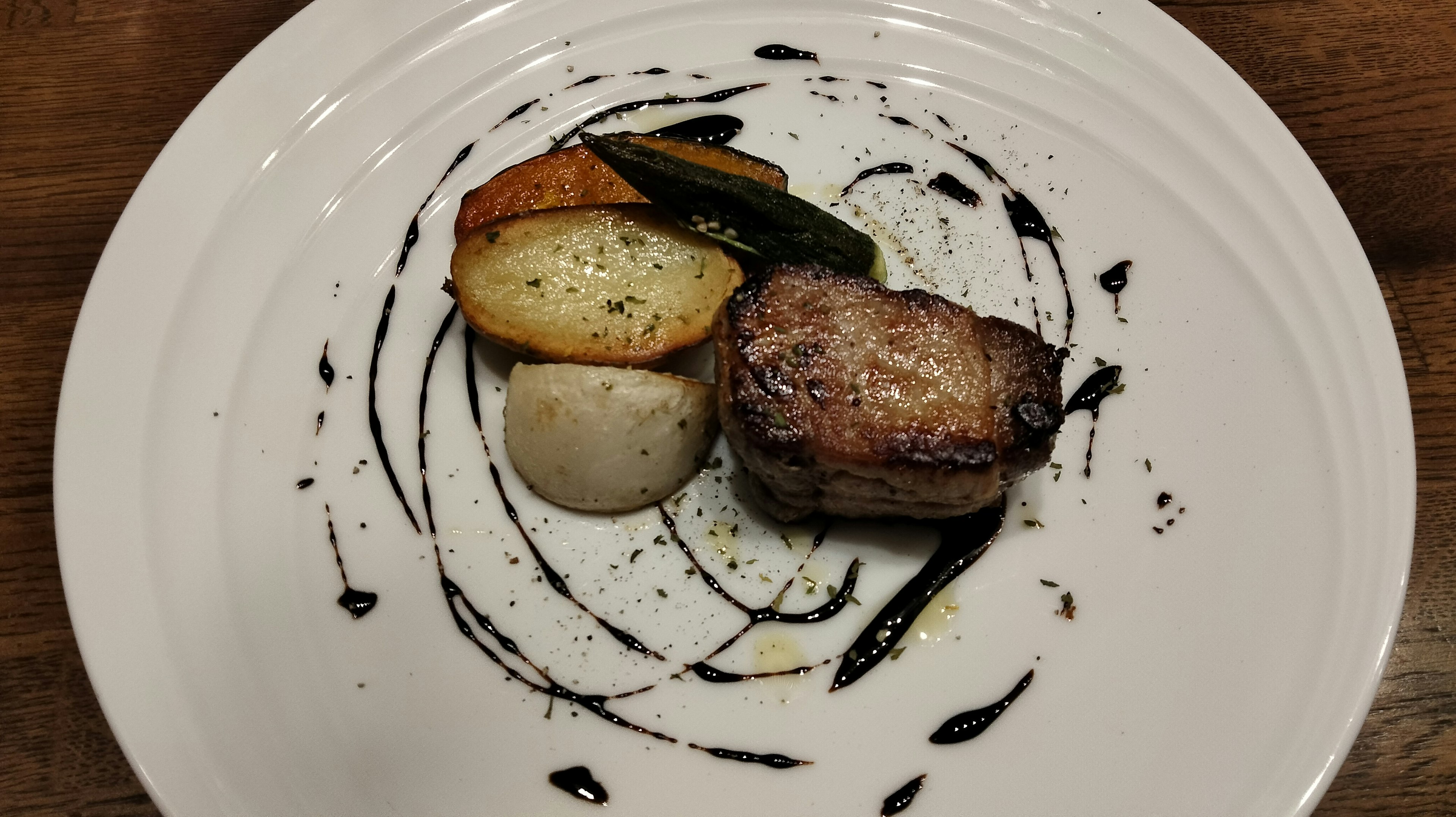 Un plat magnifiquement présenté avec de la viande et des légumes avec un tourbillon de sauce