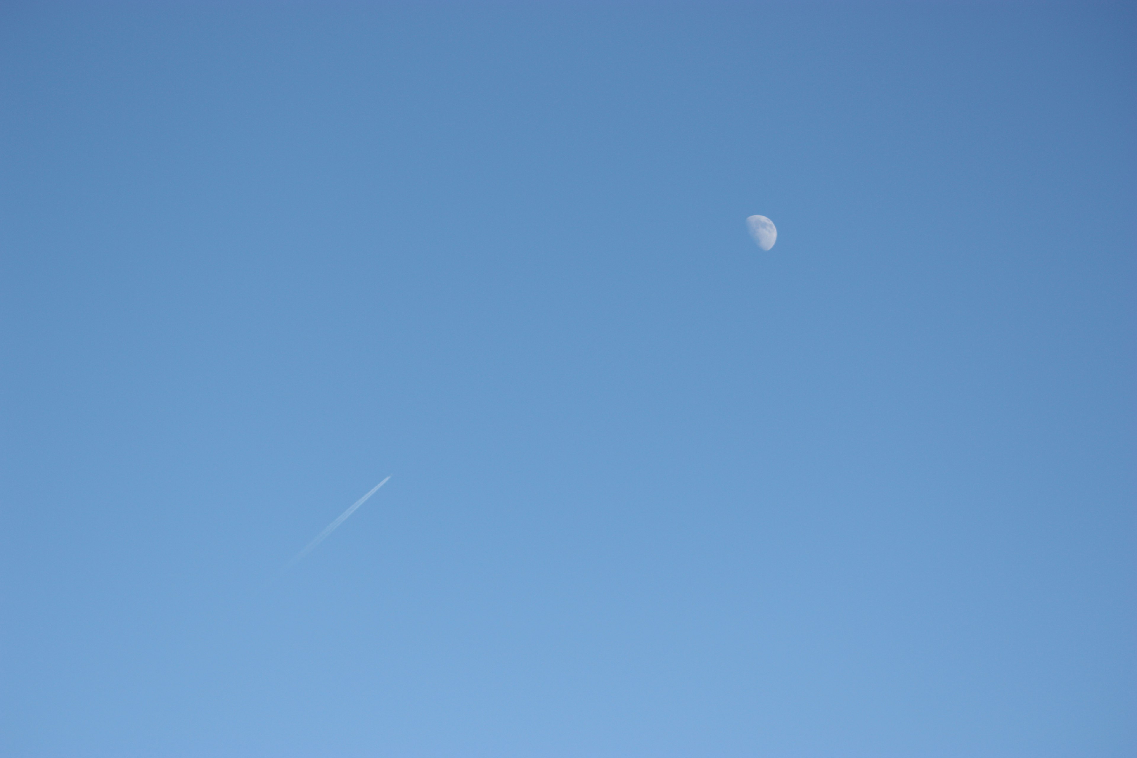 Lune dans un ciel bleu clair avec une traînée d'avion