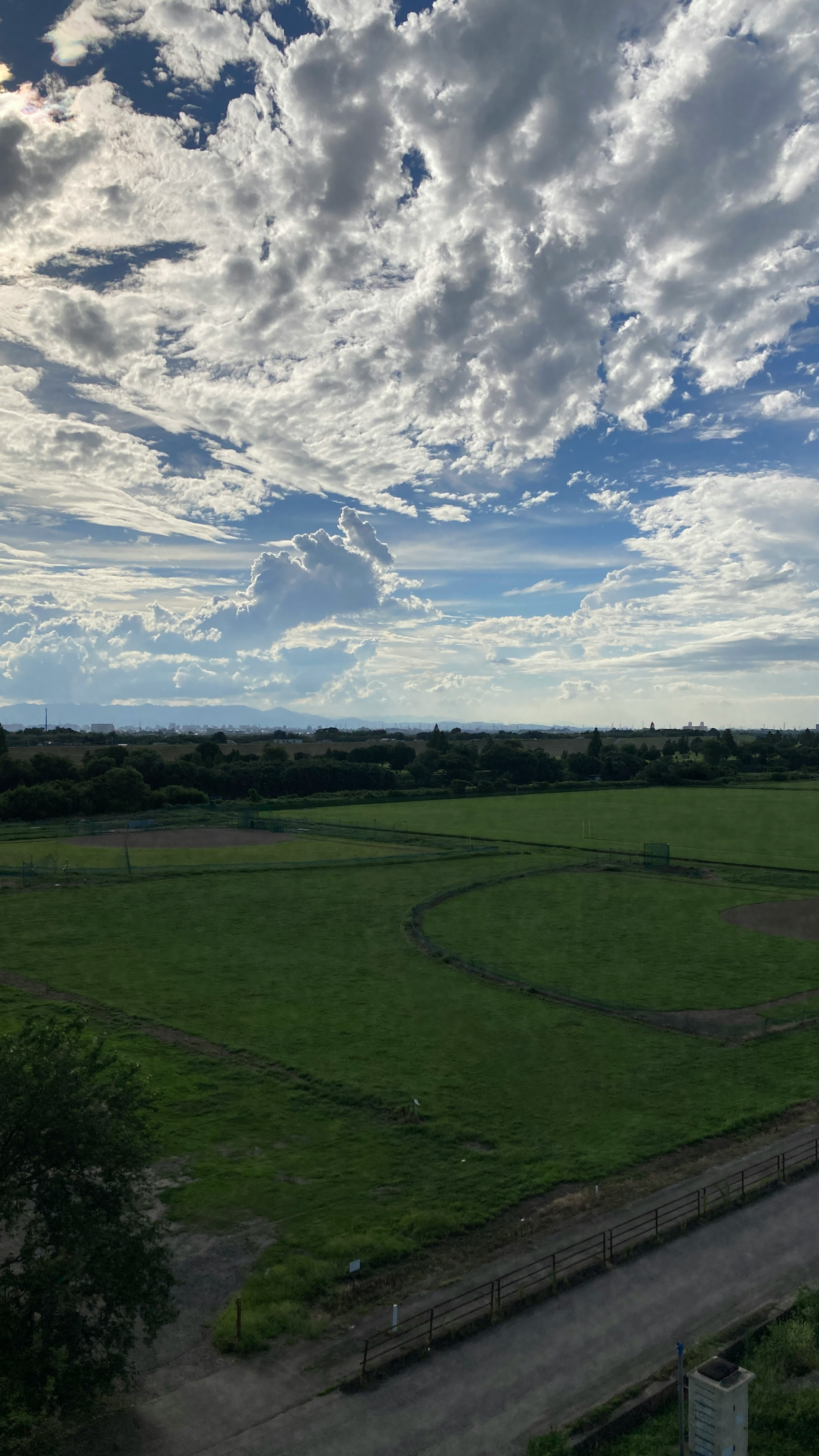 青空と白い雲が広がる風景 緑豊かな田園地帯と道が見える