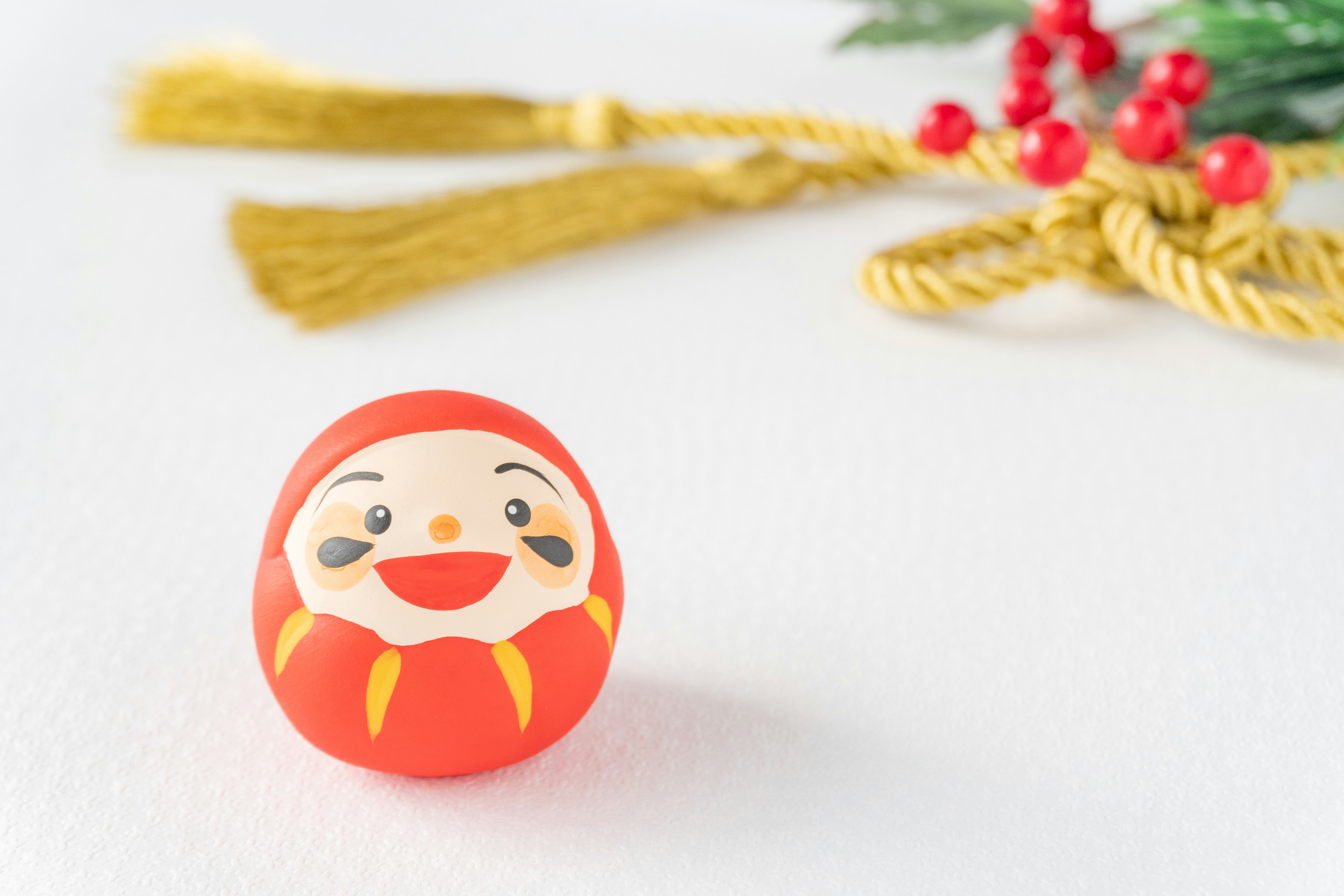 Muñeco Daruma rojo con cara sonriente contra un fondo de decoración dorada