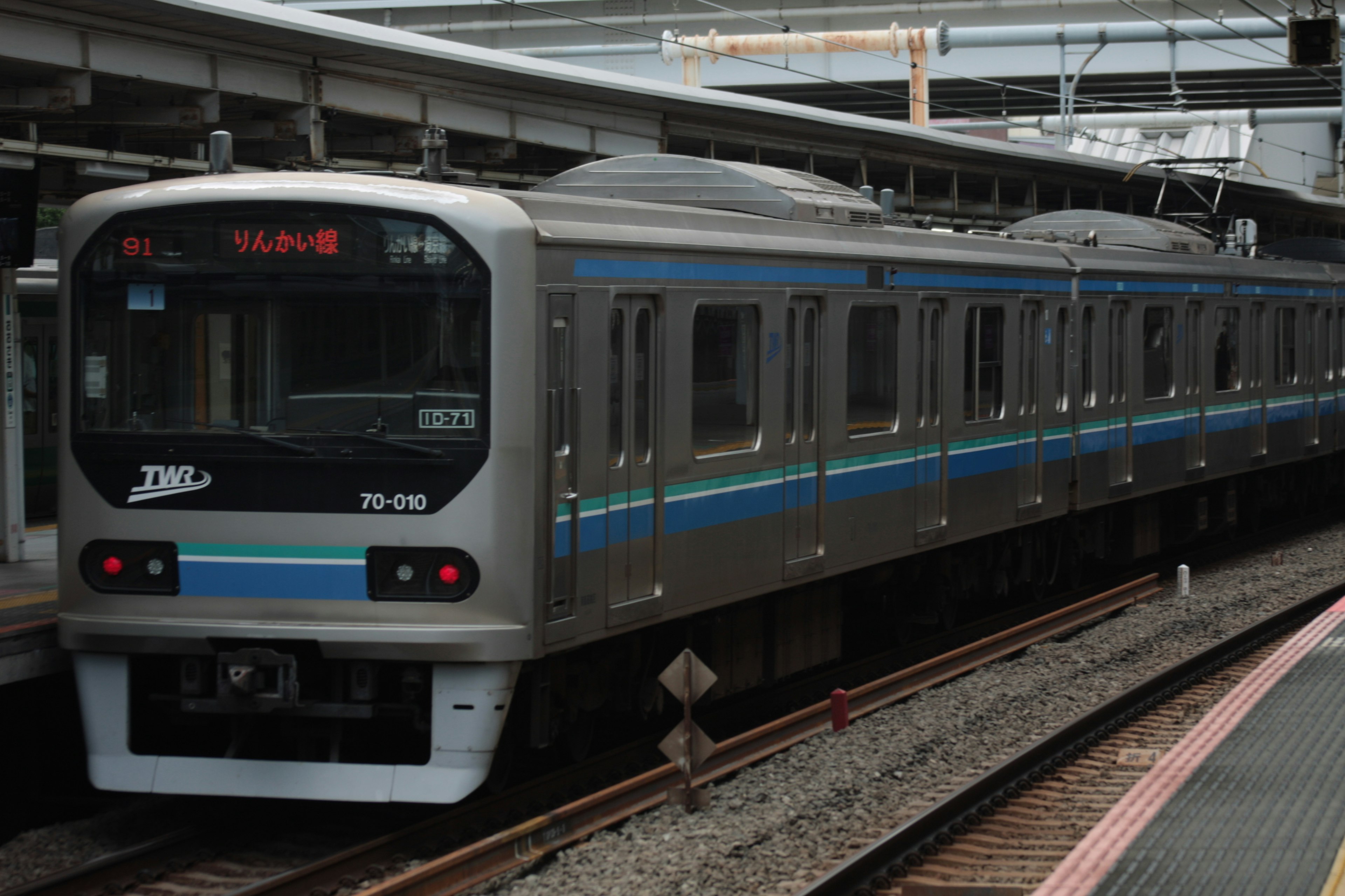 Kereta abu-abu dengan garis biru berhenti di stasiun