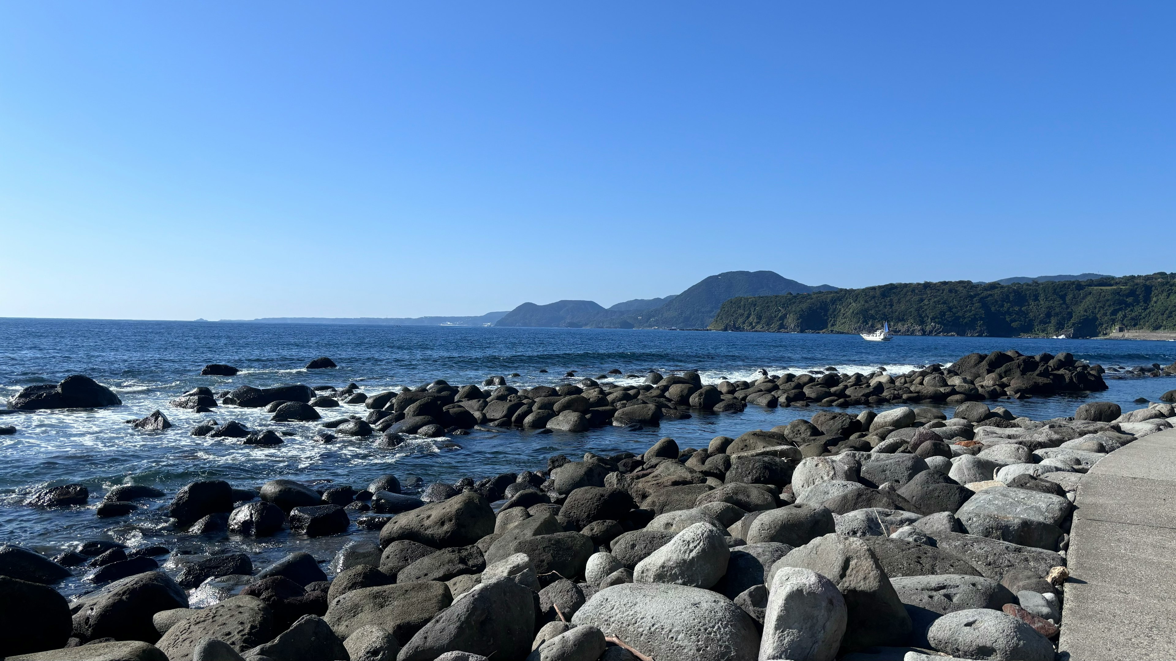 Scène côtière ensoleillée avec rivage rocheux et vagues visibles