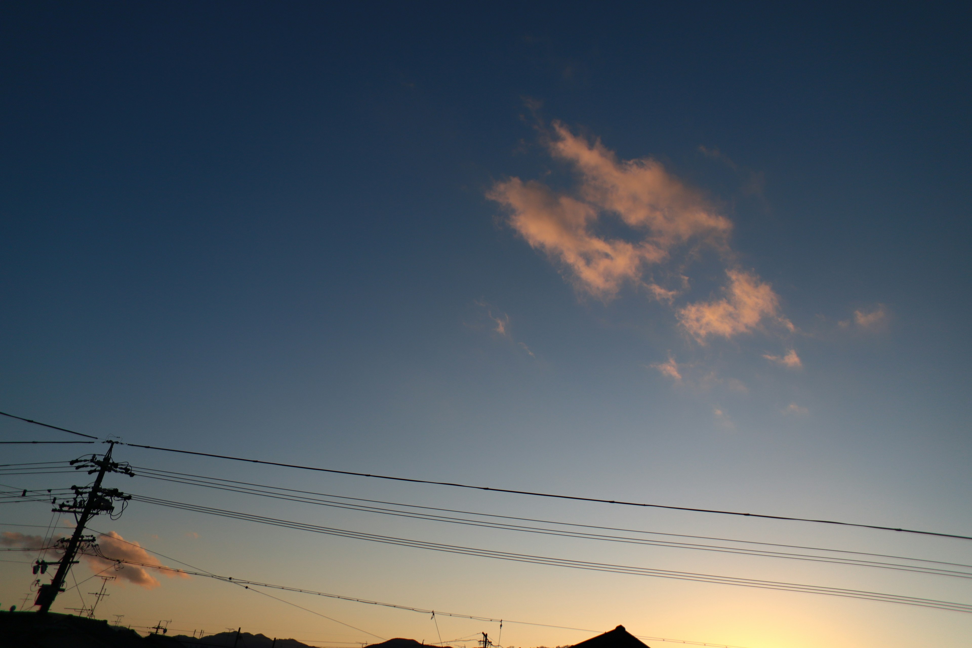 夕焼けの空に浮かぶ雲と電線のシルエット