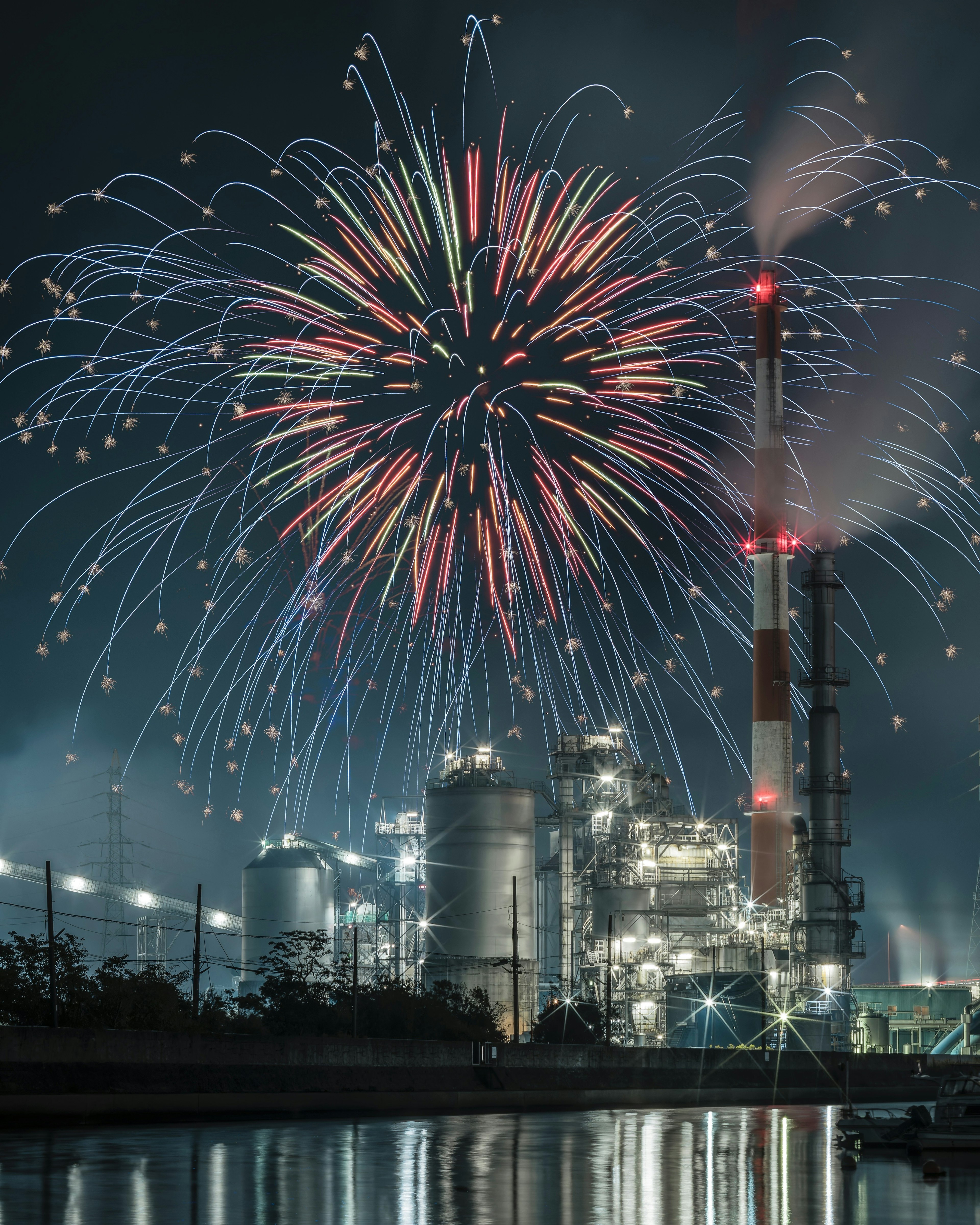 Scène nocturne avec des feux d'artifice au-dessus d'une usine industrielle