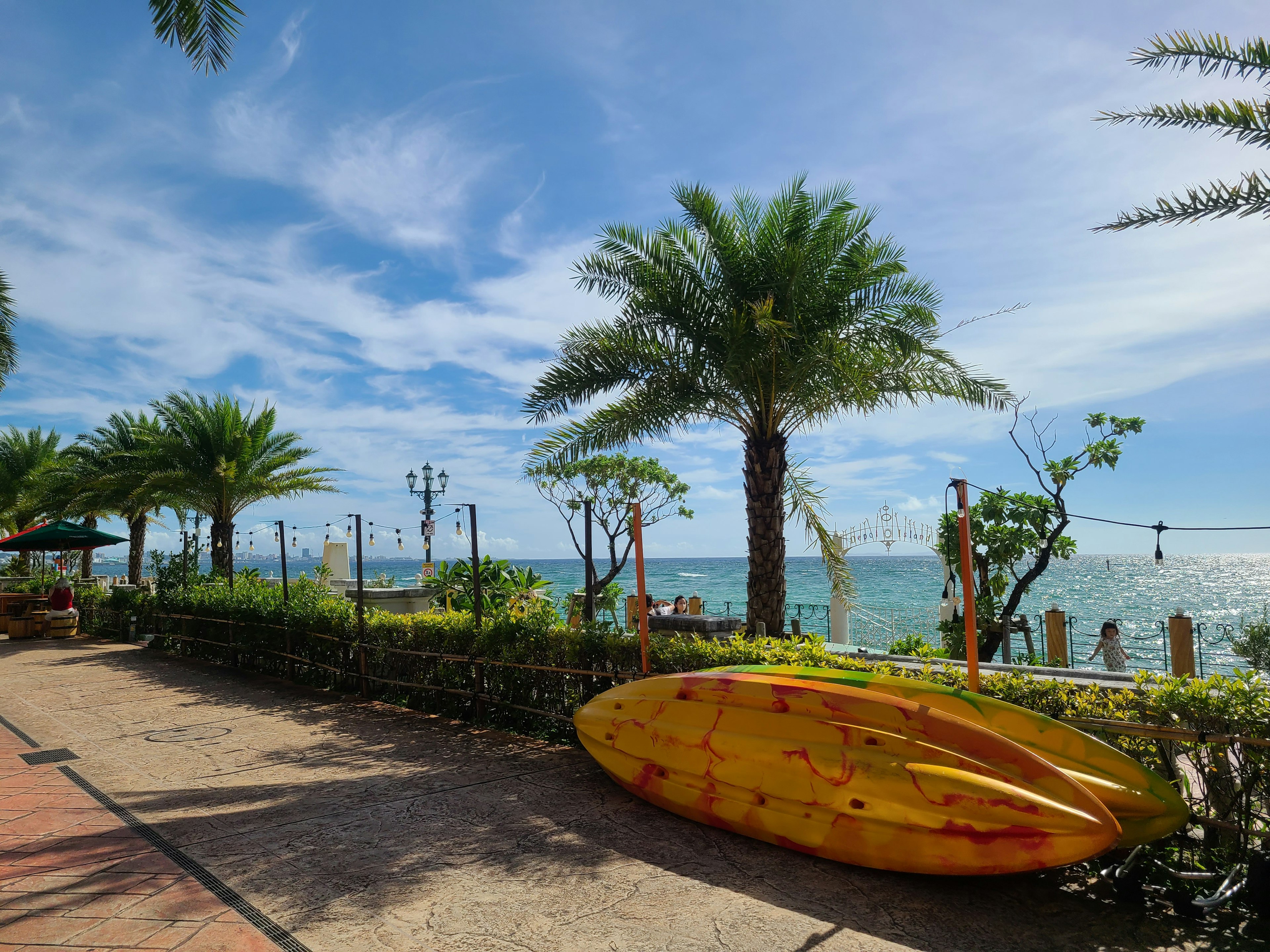 Yellow canoe next to palm trees by the blue sea and sky