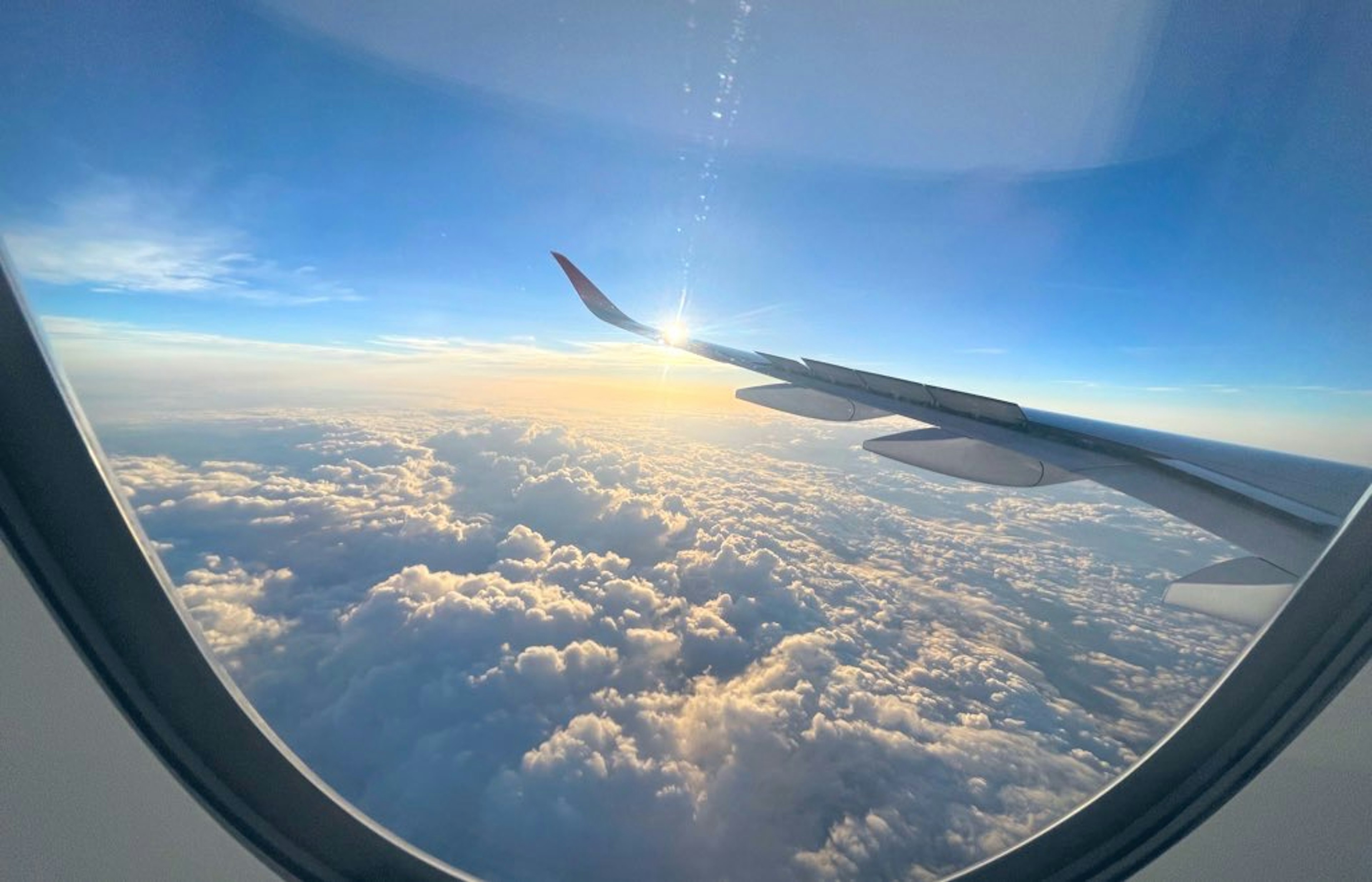 Blick aus einem Flugzeugfenster auf Wolken und Abendhimmel