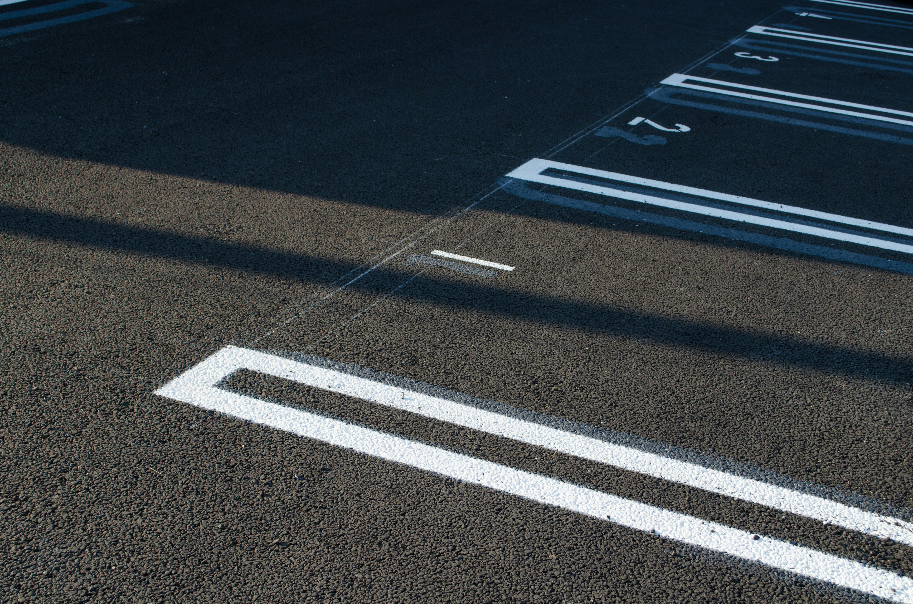 A section of asphalt parking lot with visible white parking space lines