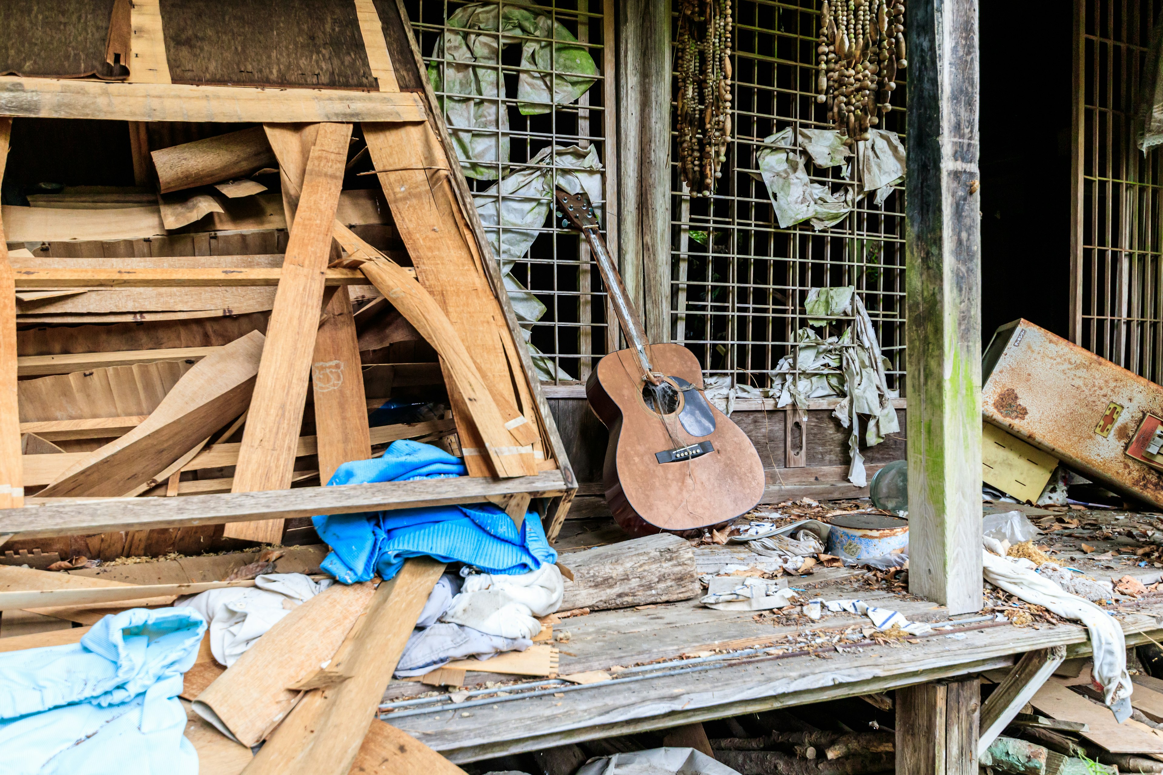 Acoustic guitar resting among scattered wood in a dilapidated shed