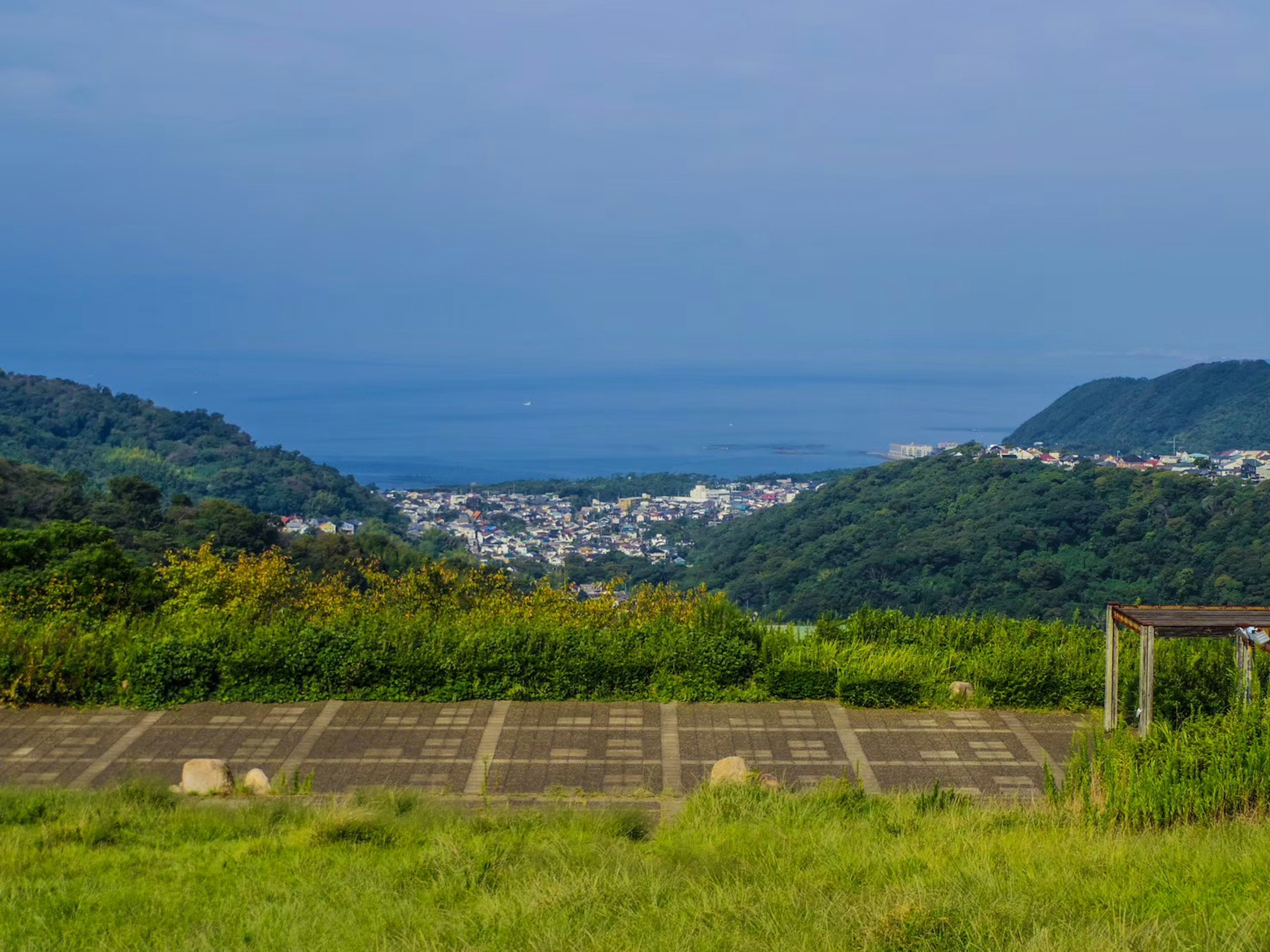 Vue pittoresque d'un village calme avec la mer bleue et des collines vertes en arrière-plan