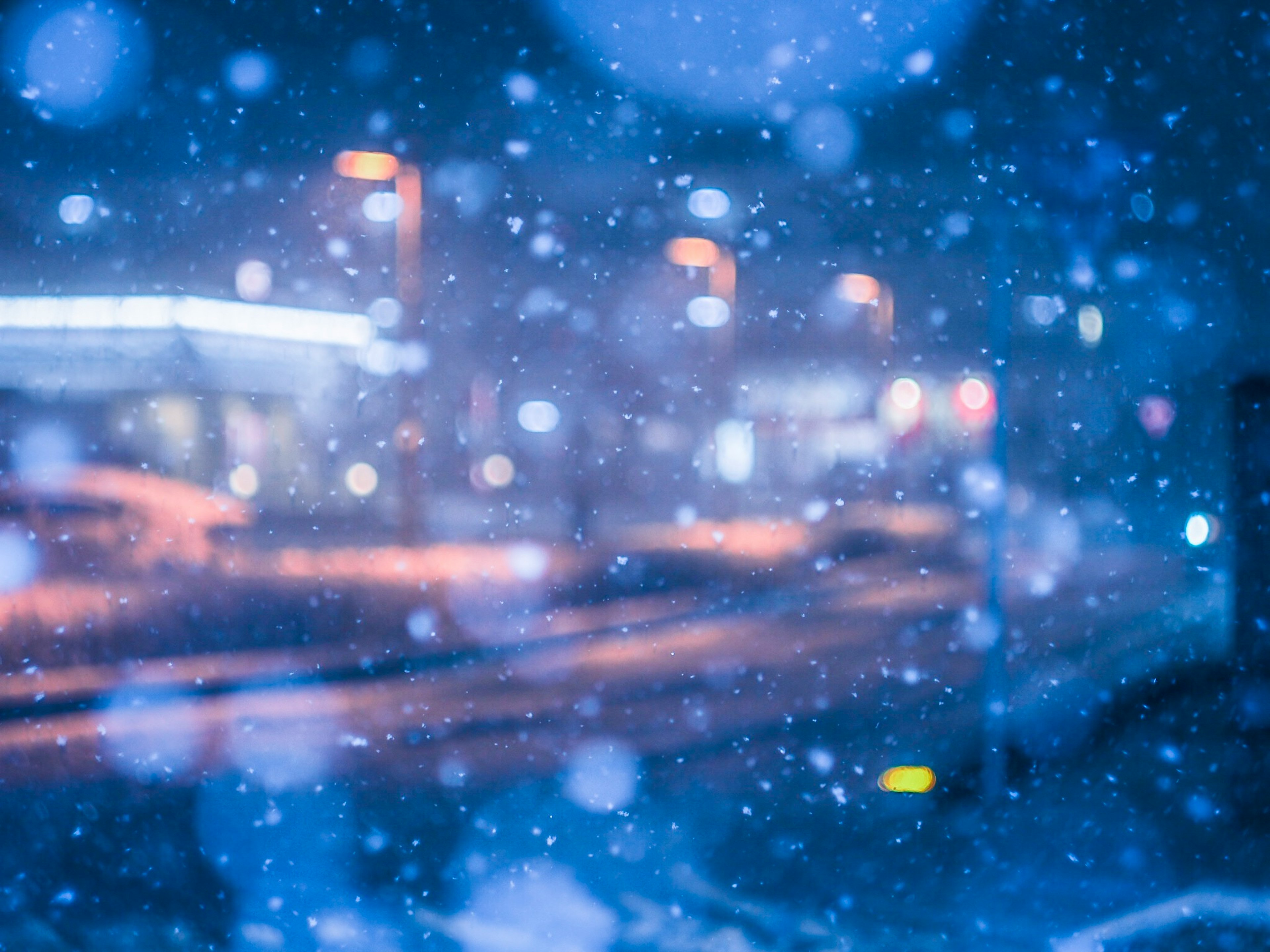 Lumières de la ville floues sous la neige avec un fond bleu