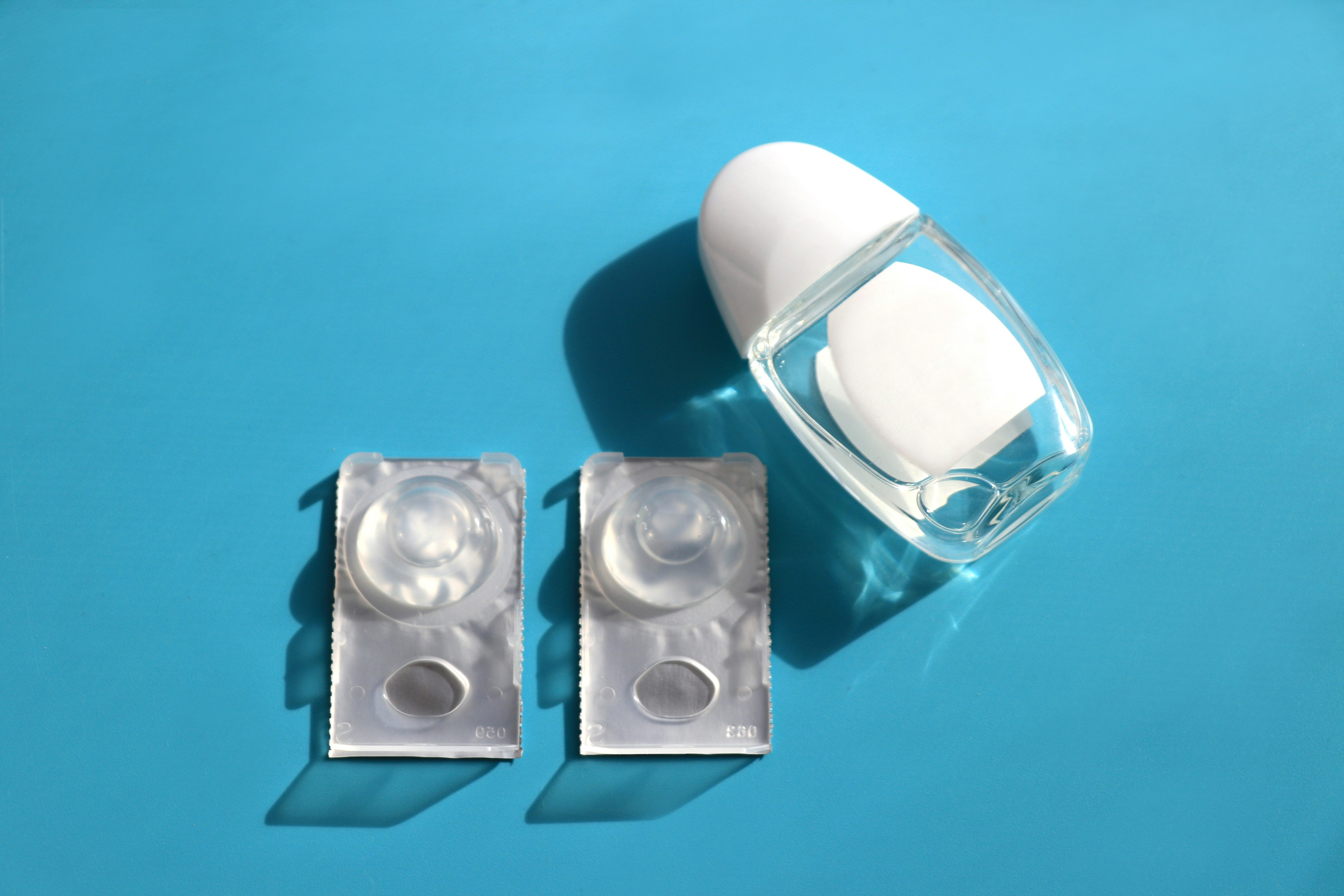 Clear container with white roller and two clear bottles on a blue background