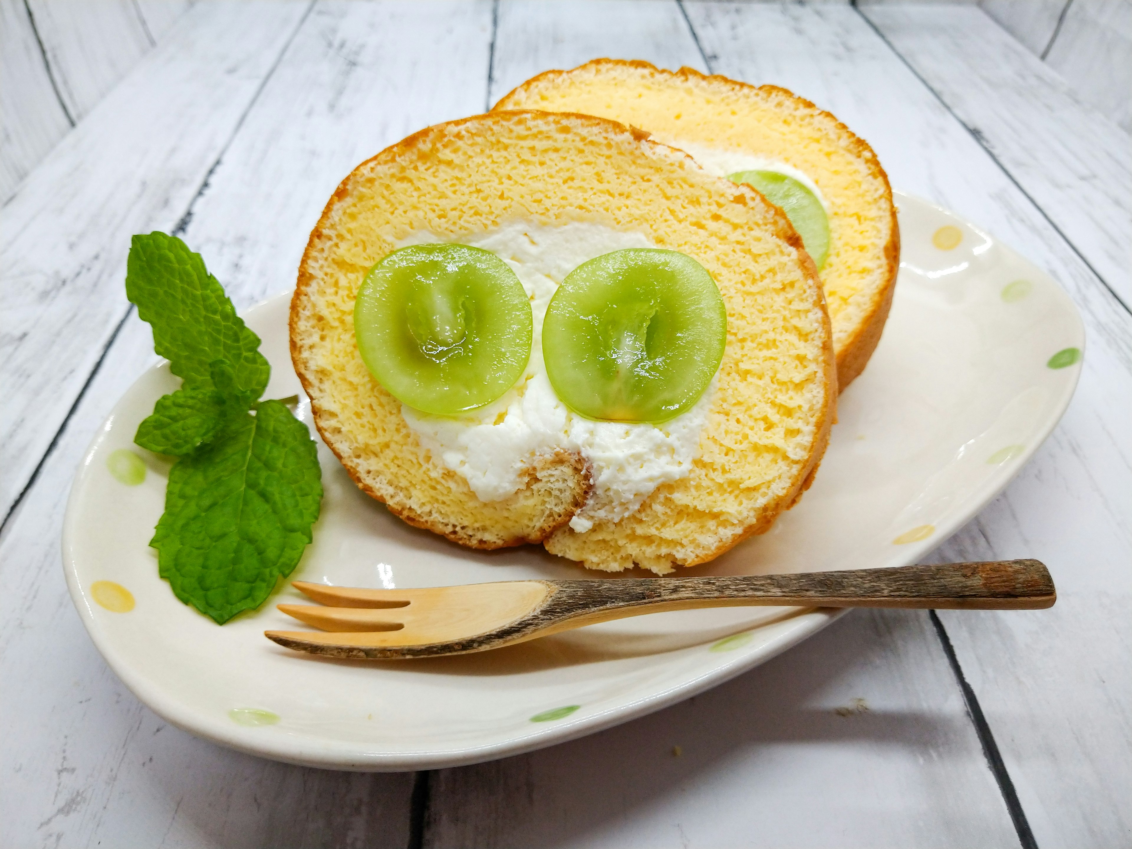 Pastel esponjoso cubierto con crema y rodajas de fruta verde