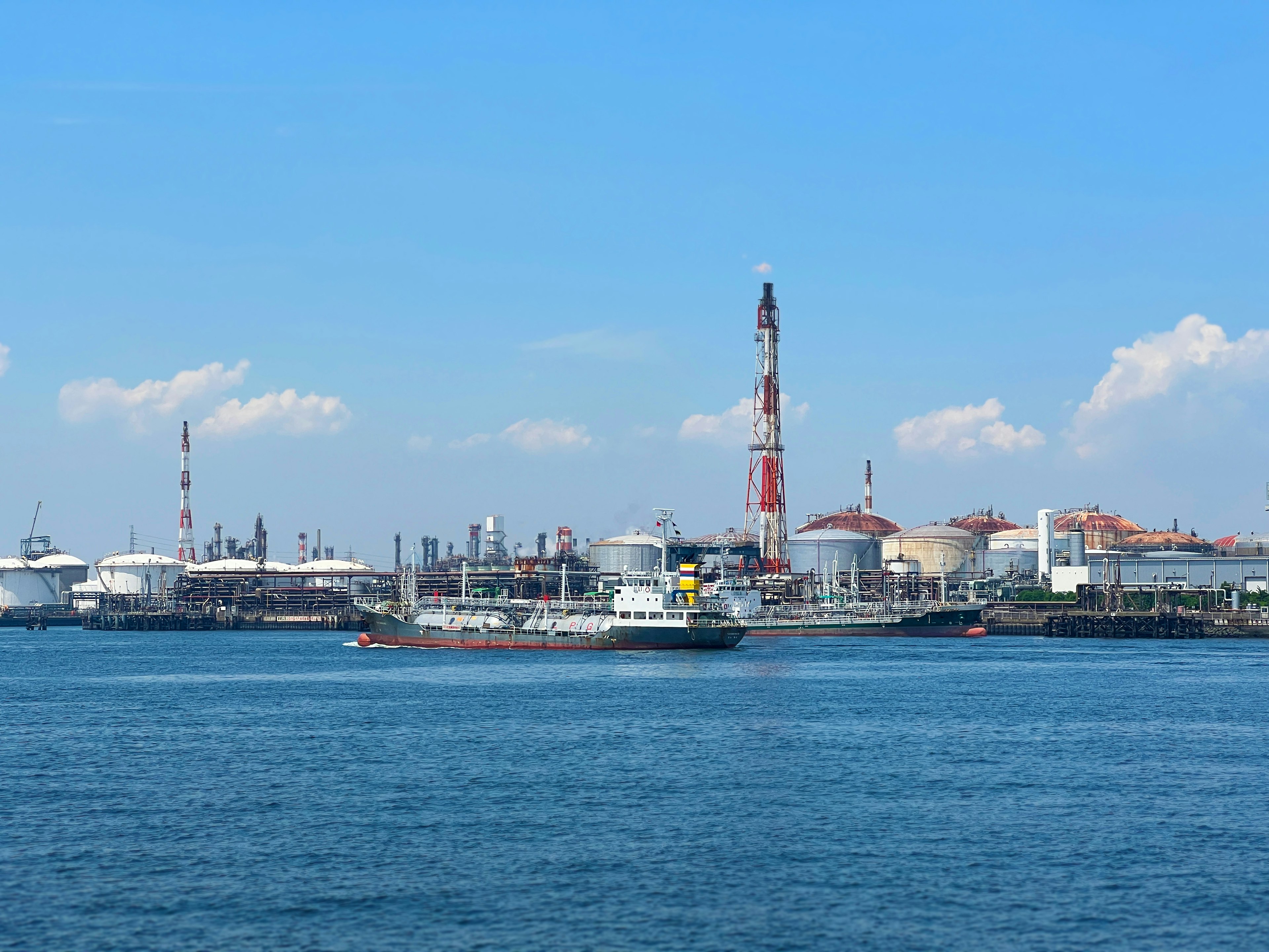 Area industri di tepi laut dengan langit biru cerah dan permukaan air