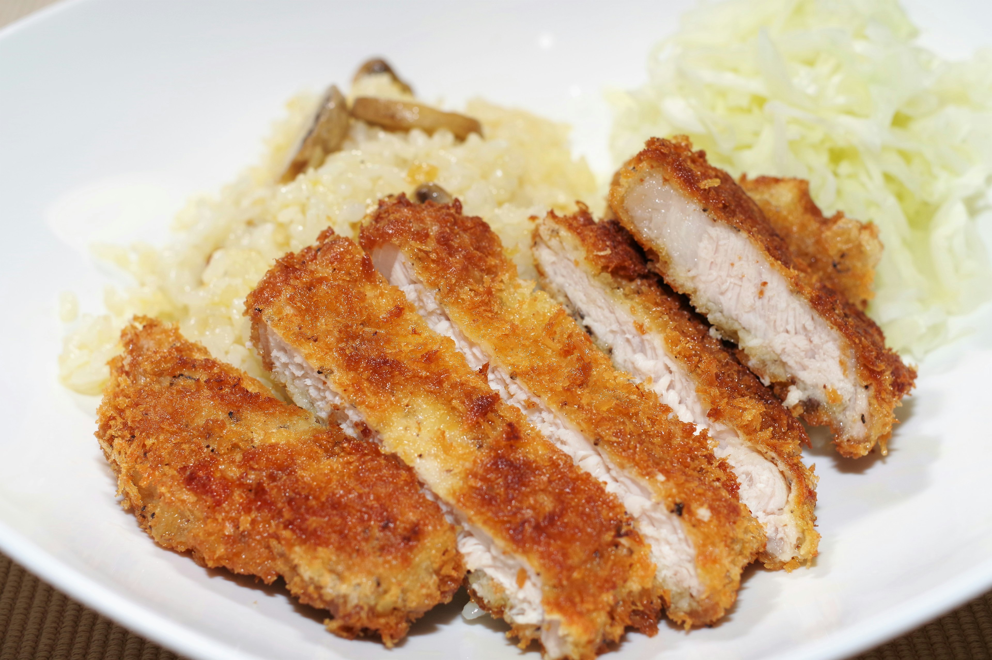 Cotoletta di maiale impanata a fette servita con riso e cavolo tritato