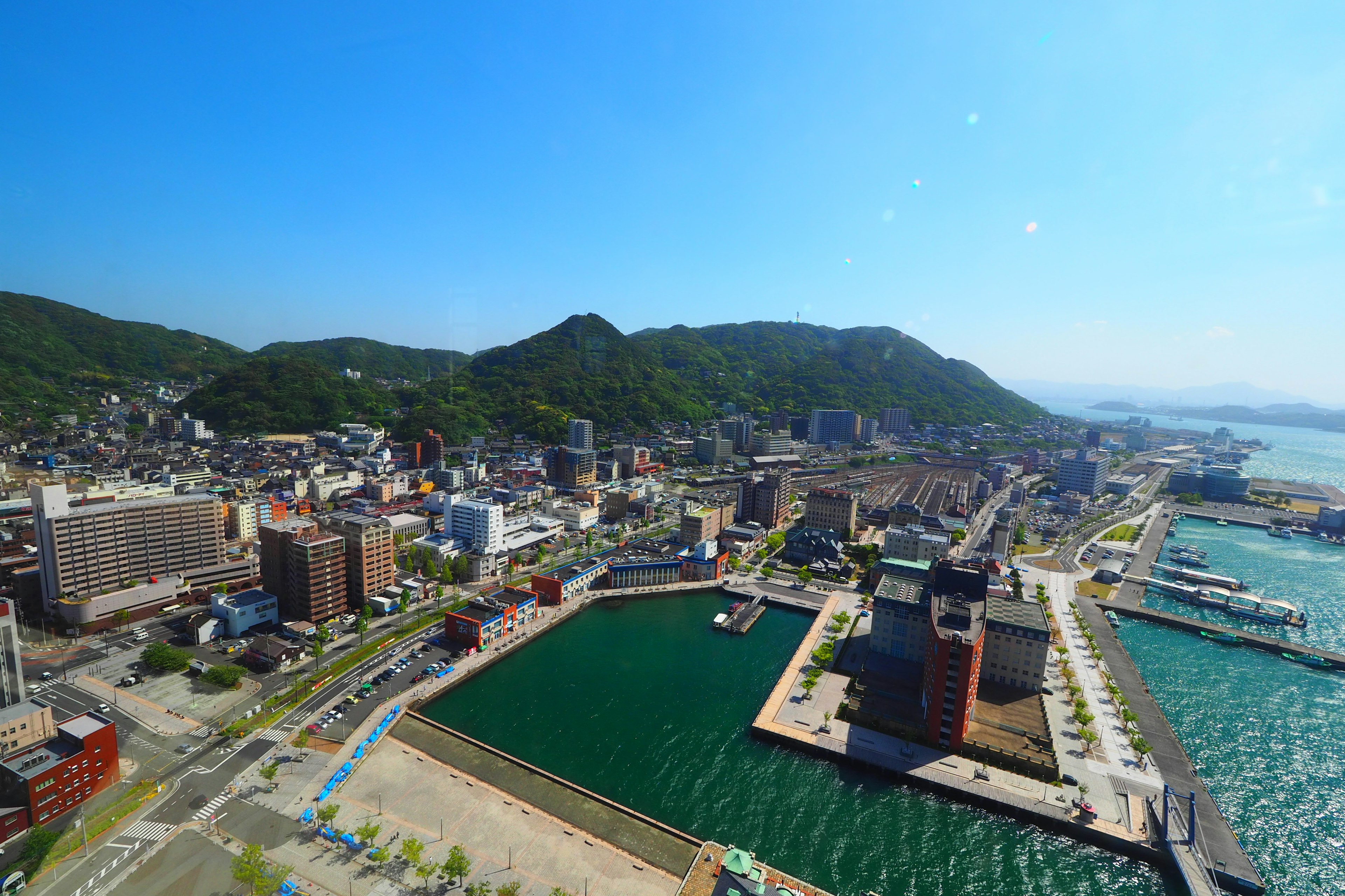 Aerial view of a port city with a green bay and blue sea