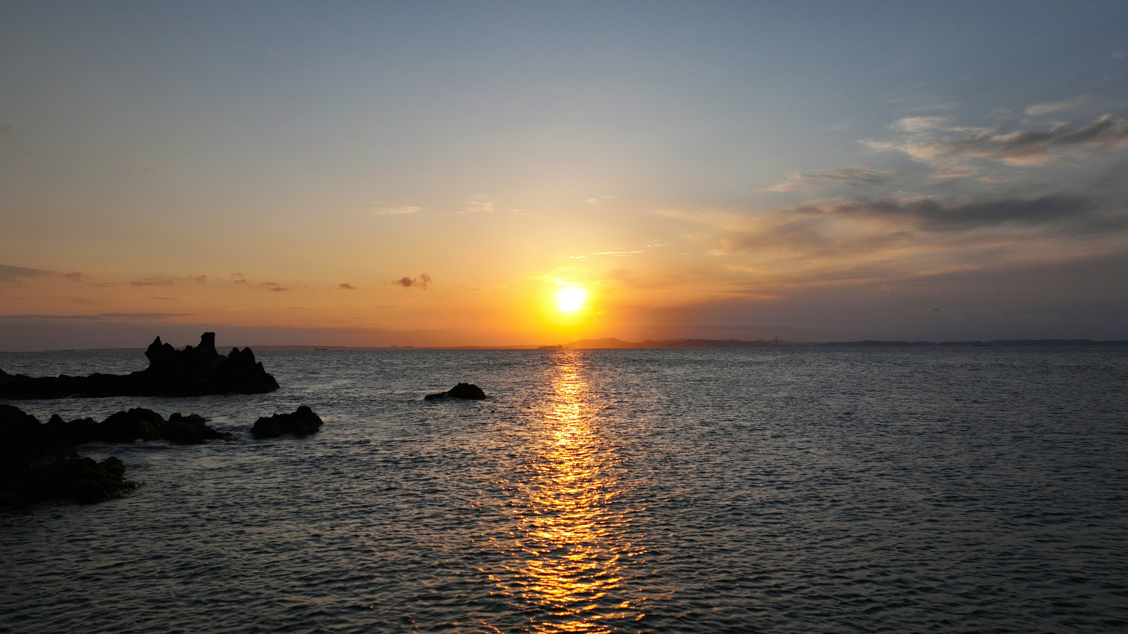 美丽的日落在海上与岩石海岸