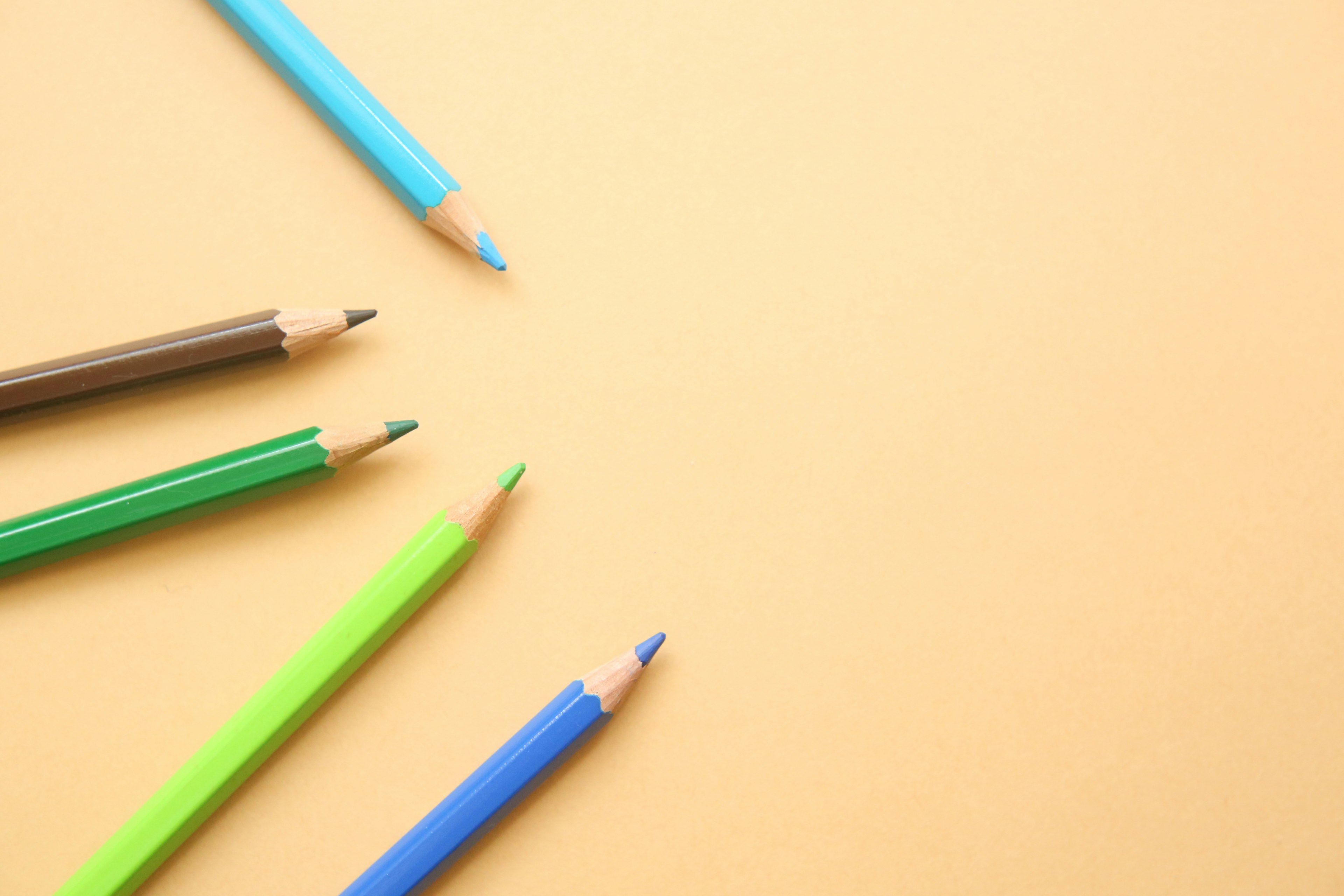 Colorful colored pencils arranged on an orange paper background