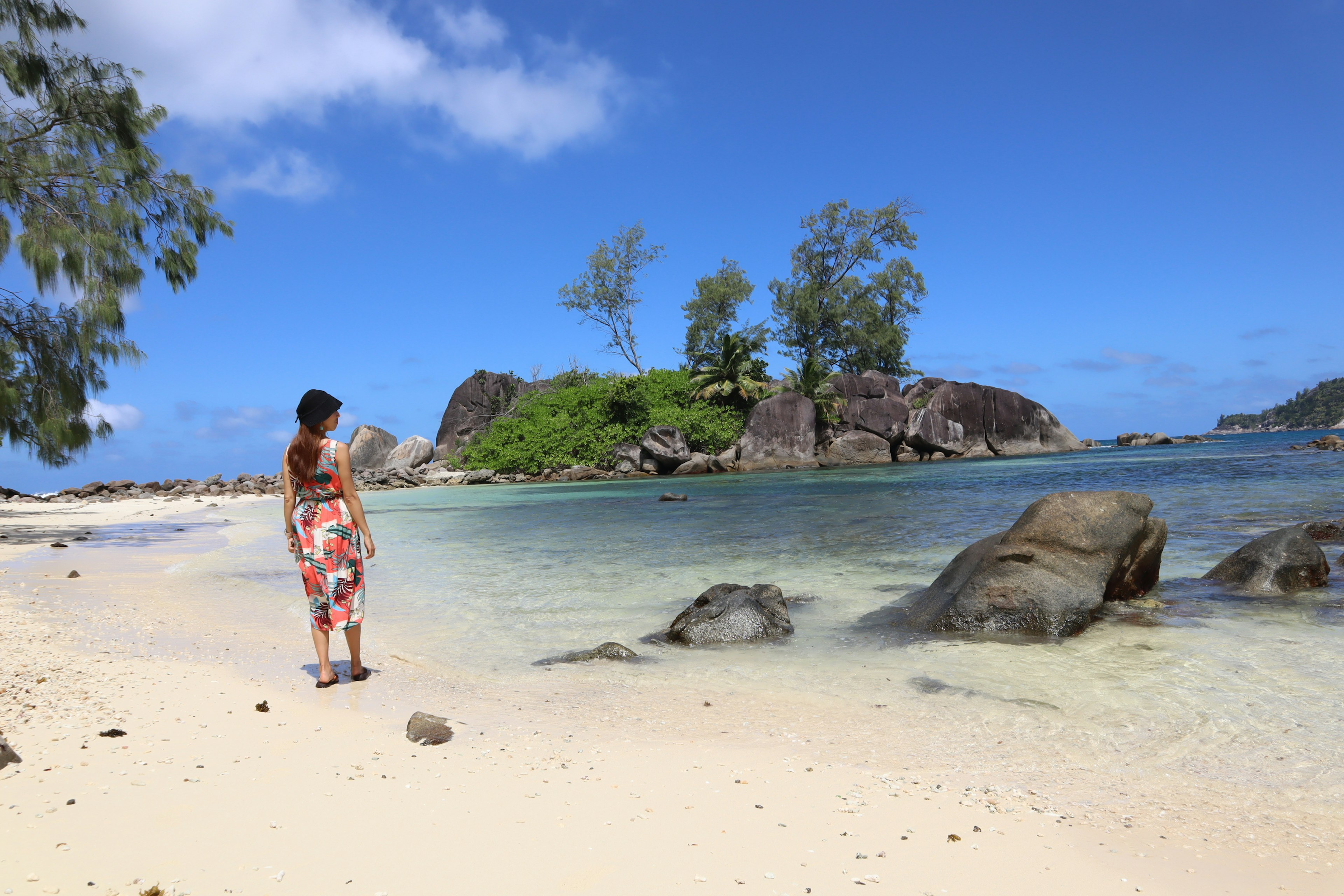 Wanita berdiri di pantai melihat ke pulau