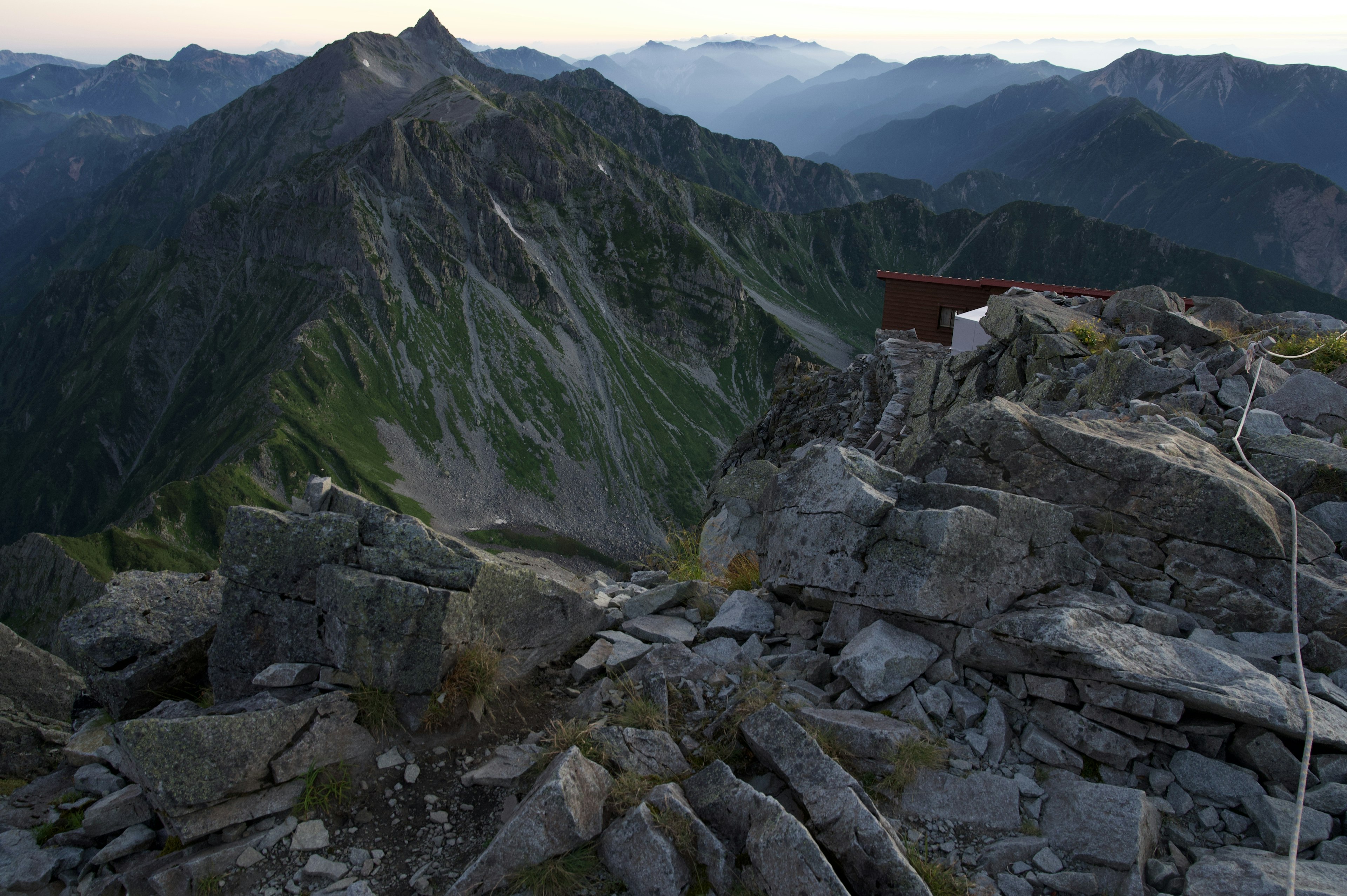 Vue depuis le sommet de la montagne avec un terrain rocheux et des montagnes lointaines