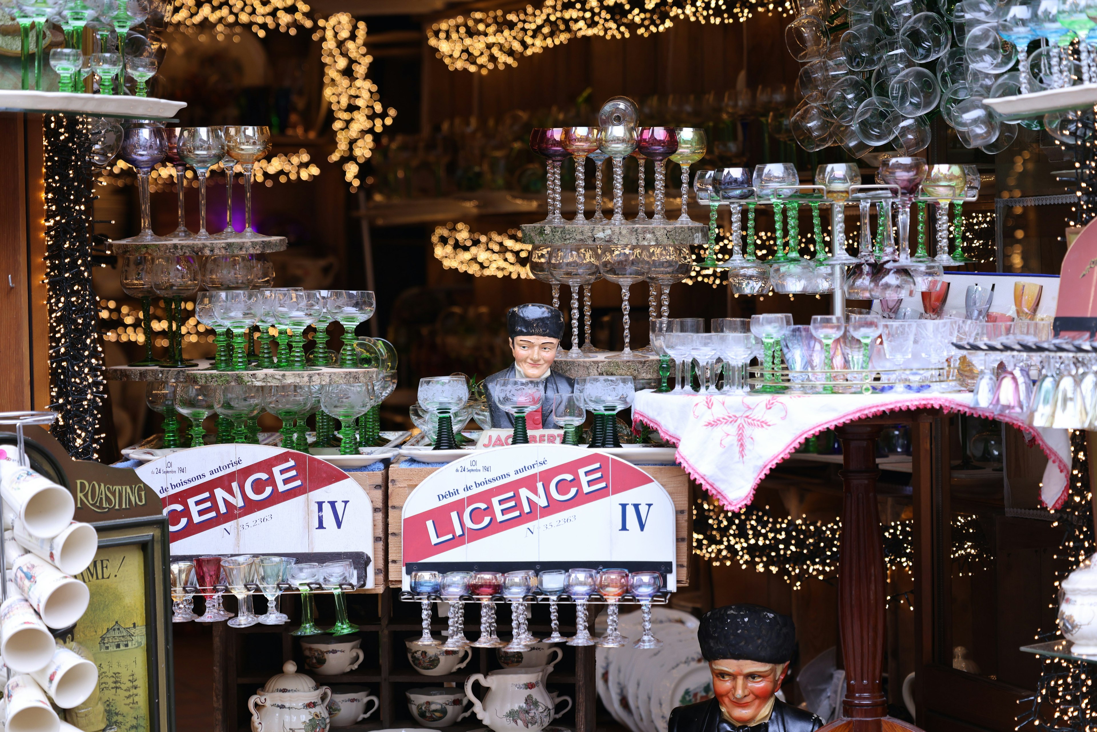 Storefront displaying colorful bottles and glasses with a license sign