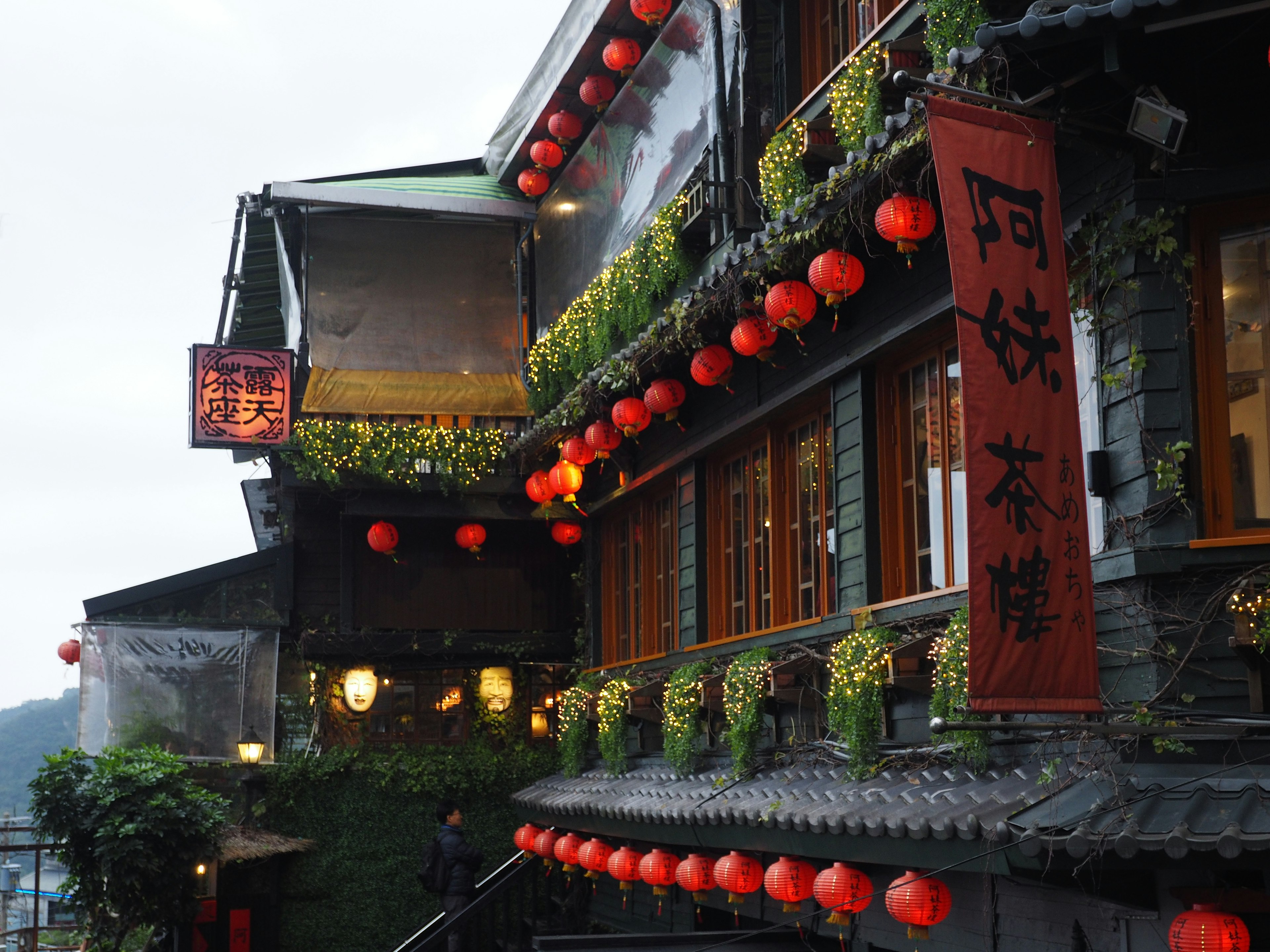 Traditional building adorned with red lanterns and flowers in an evening setting