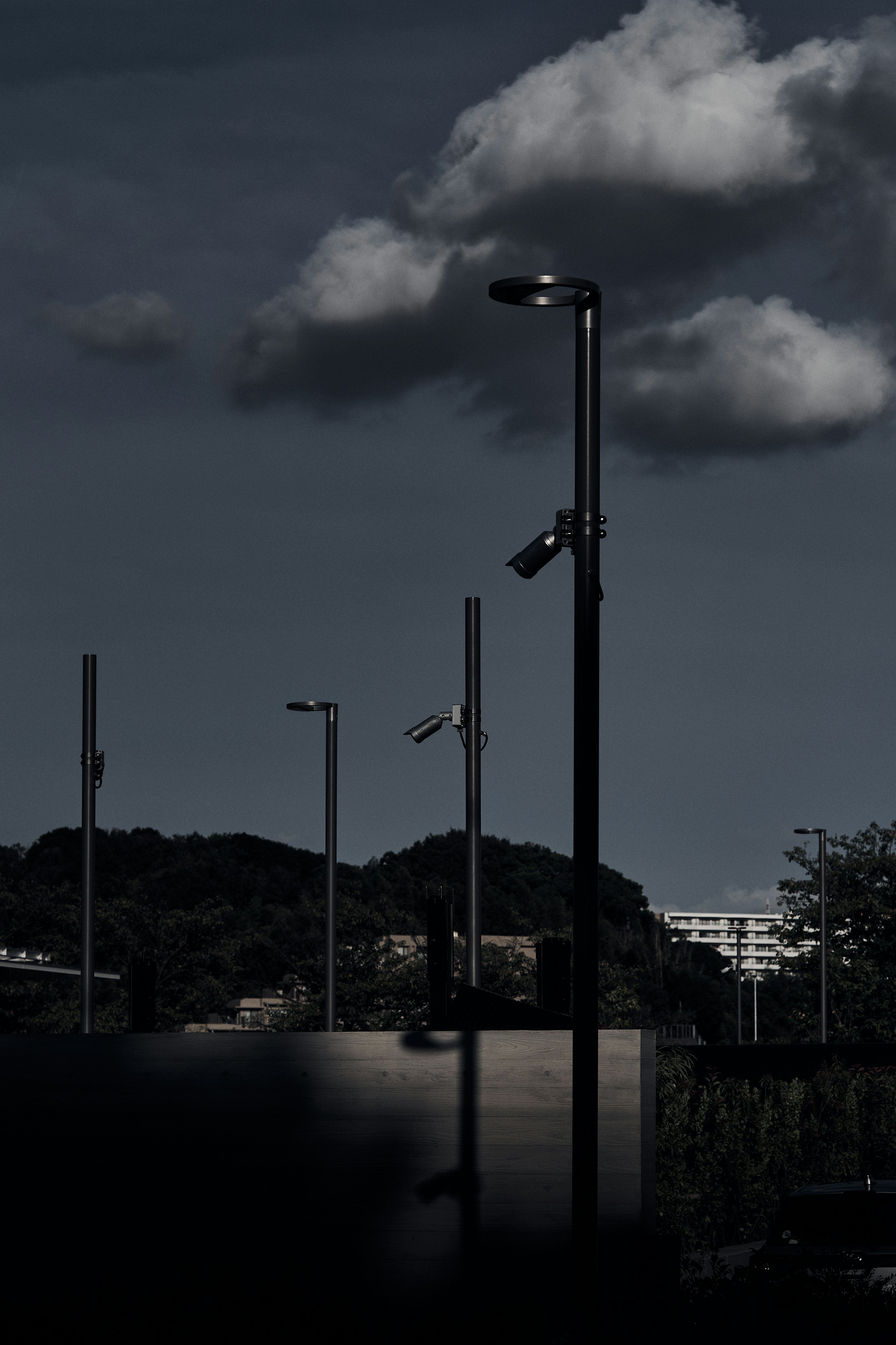 暗い雲が浮かぶ中に街灯が立ち並ぶ風景