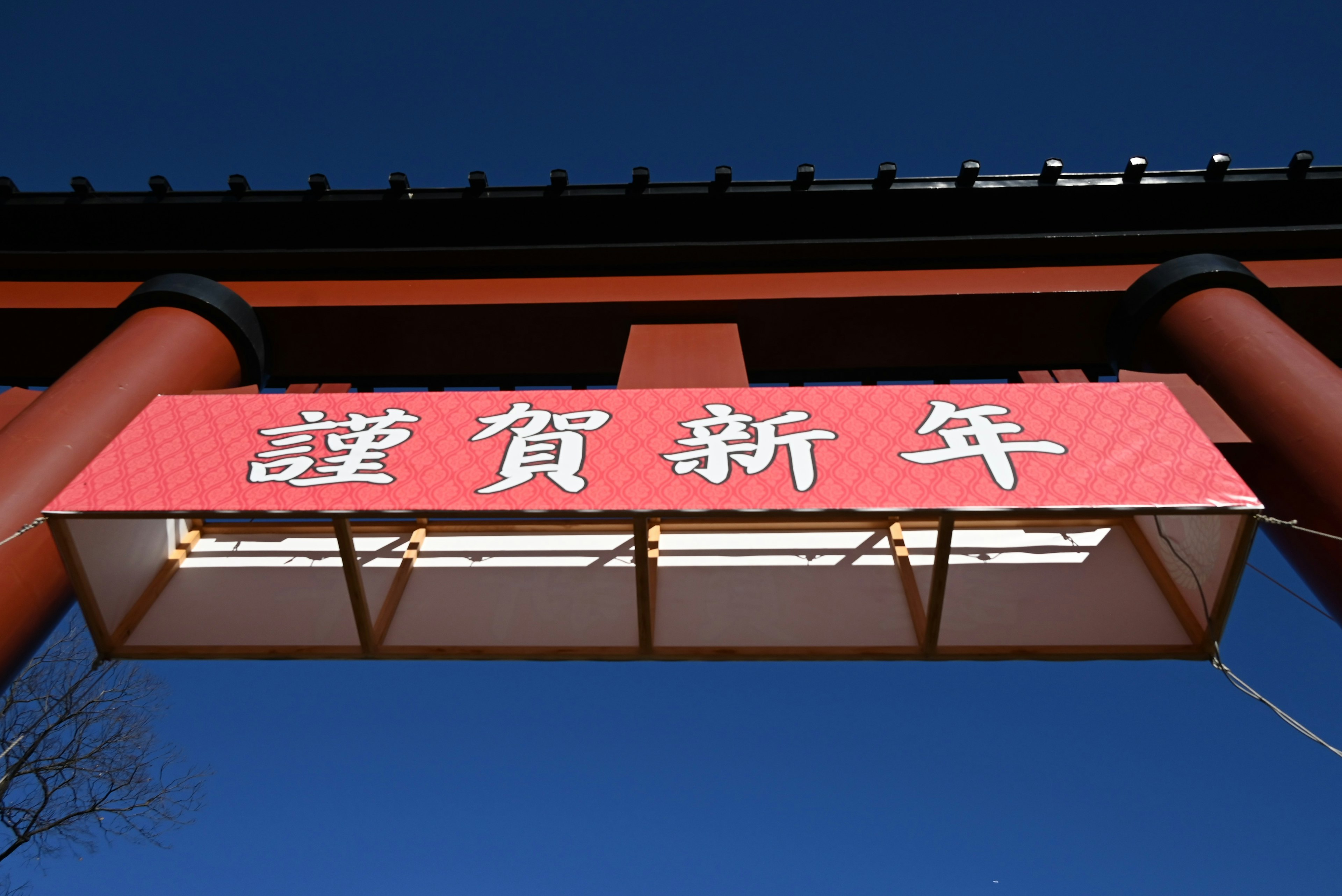 A torii gate with a red banner displaying New Year greetings