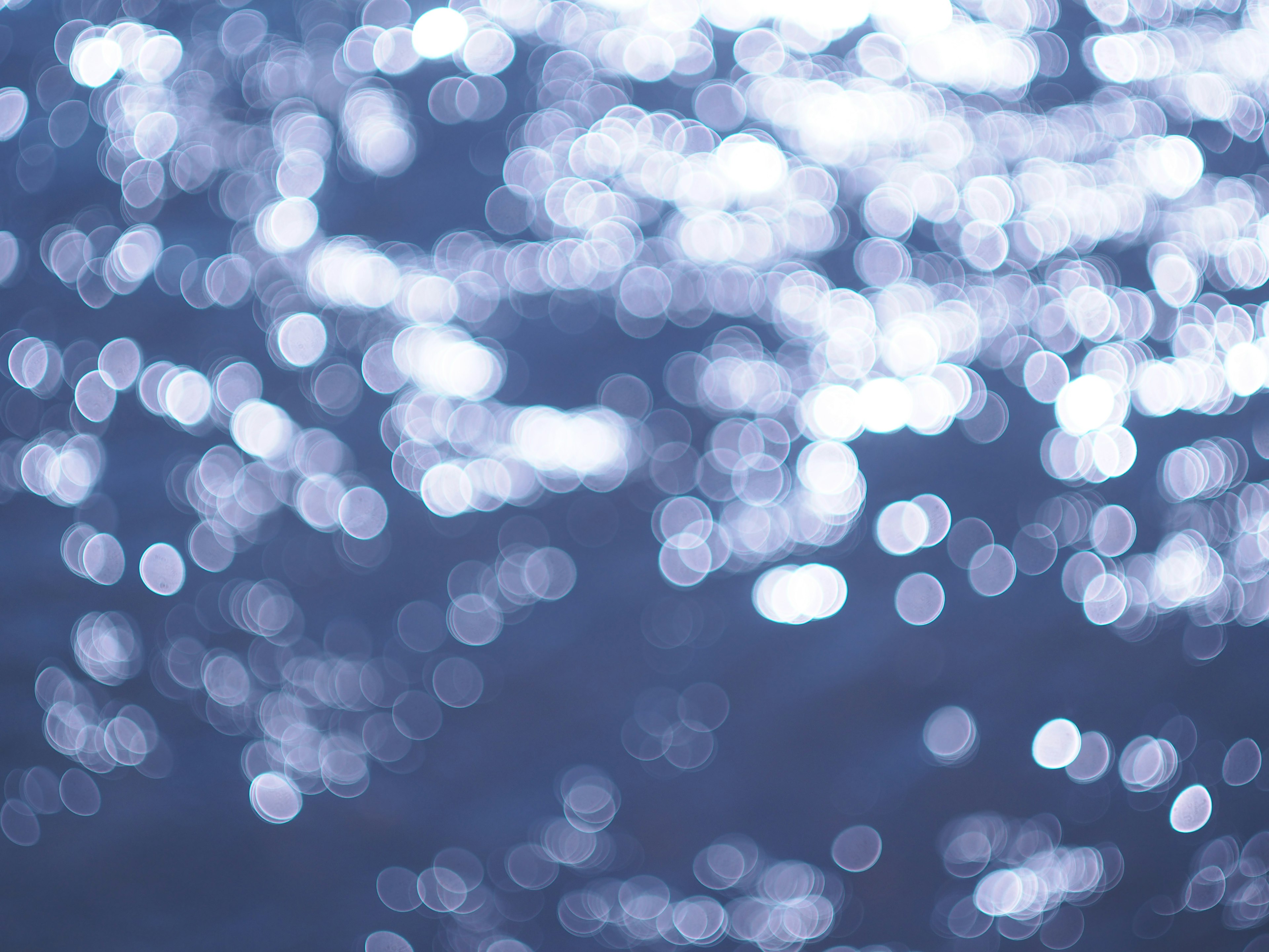 Blurred reflections of light on a blue water surface