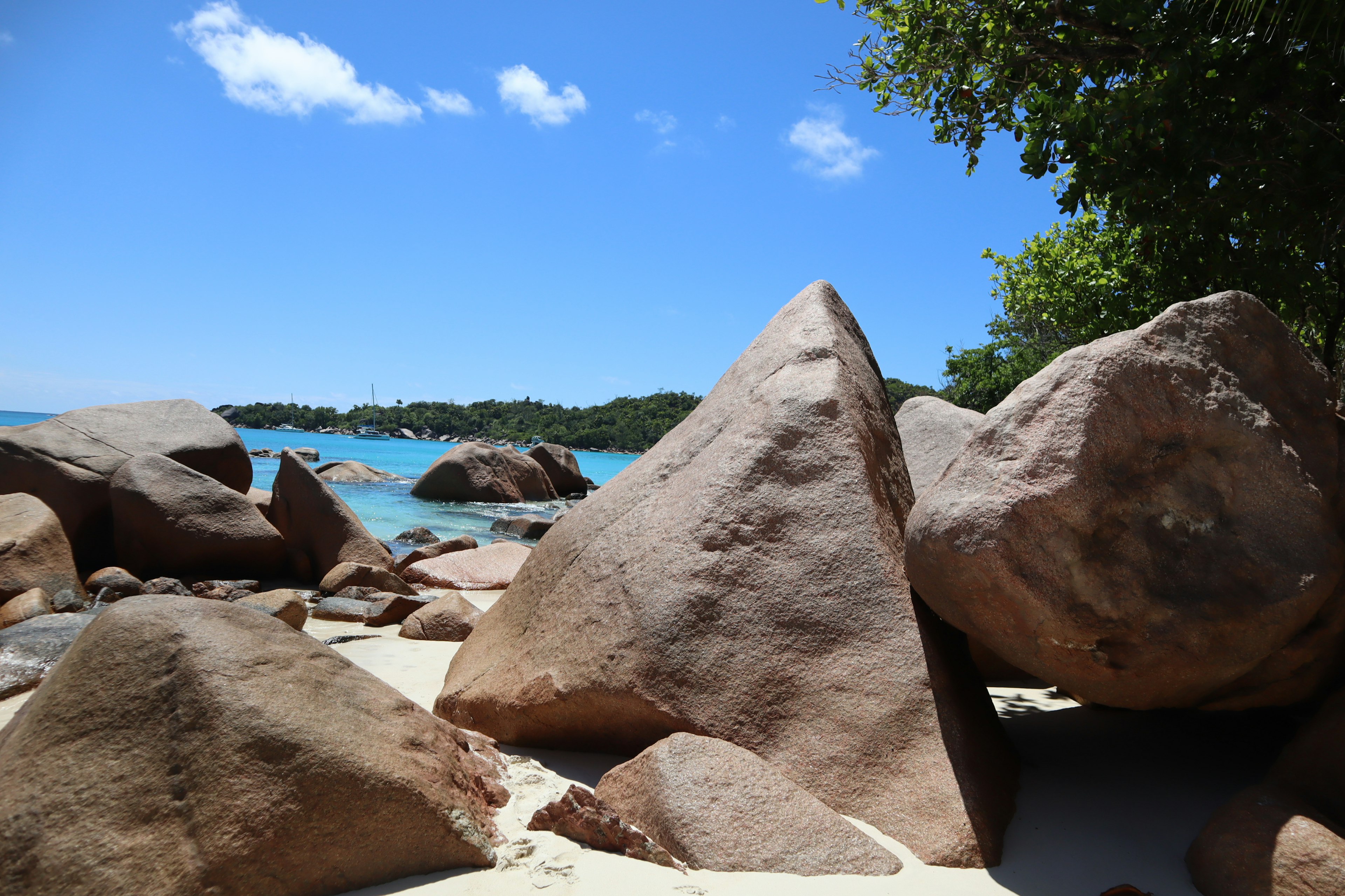 Strandszene mit großen Felsen umgeben von blauem Meer und Himmel