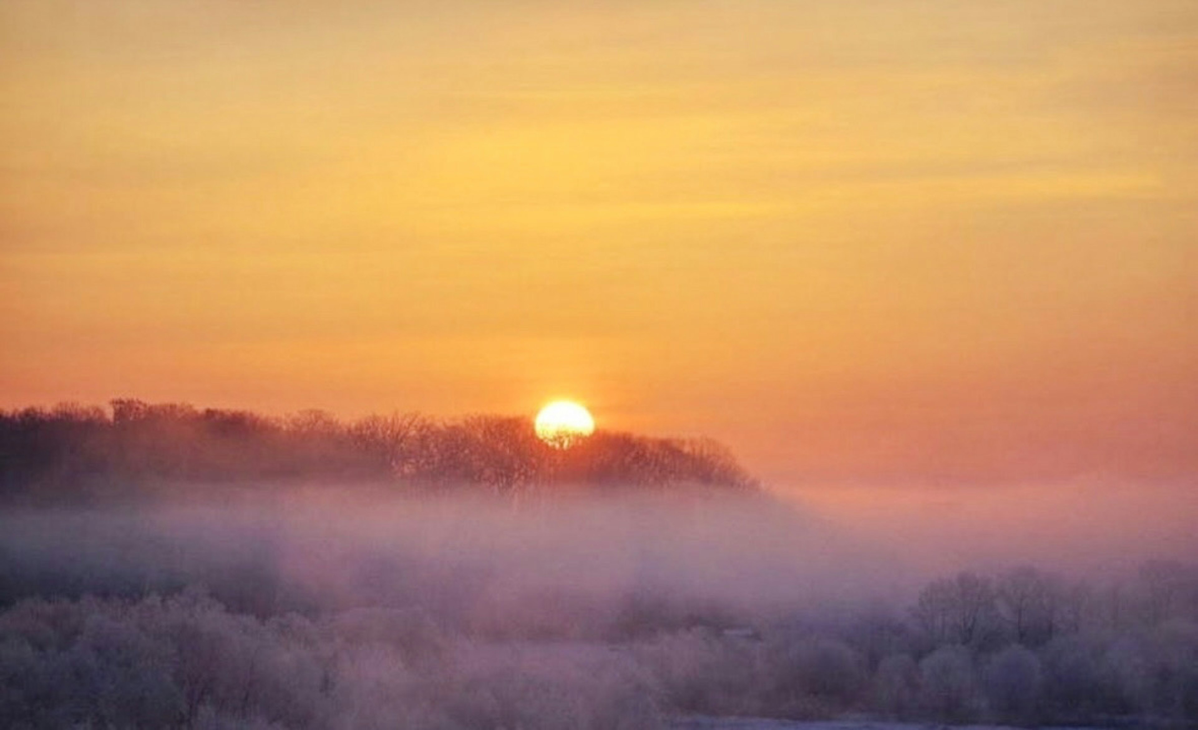 Lever de soleil sur des collines brumeuses avec ciel orange