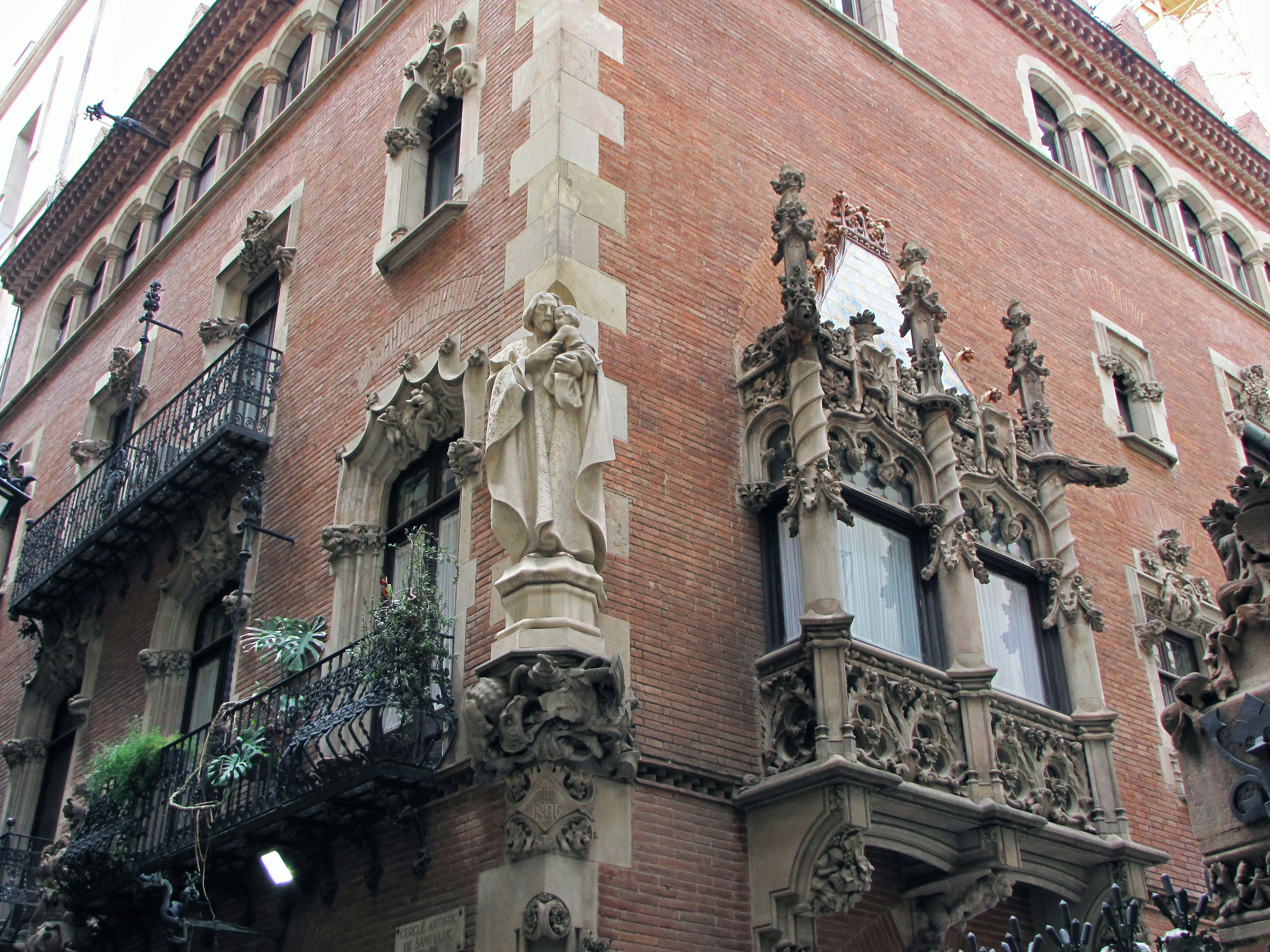 Corner of a brick building featuring ornate balconies and sculptures