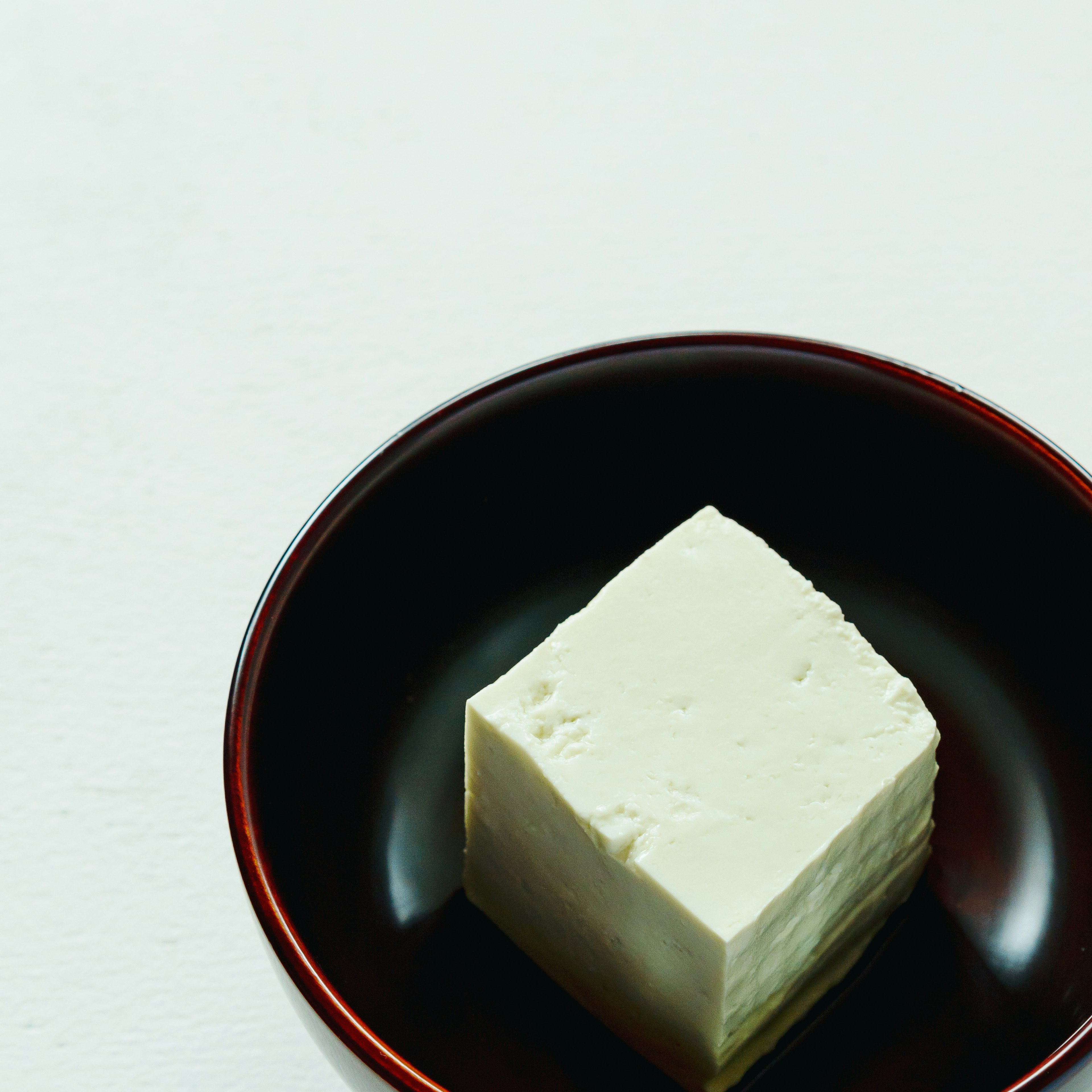 A block of white tofu placed on a black plate